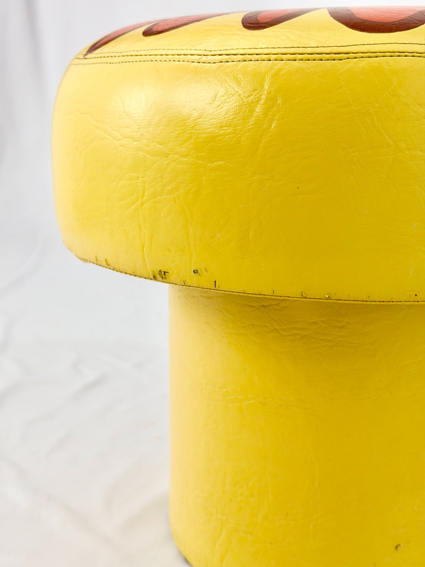 Yellow ottoman with a textured top on a white background