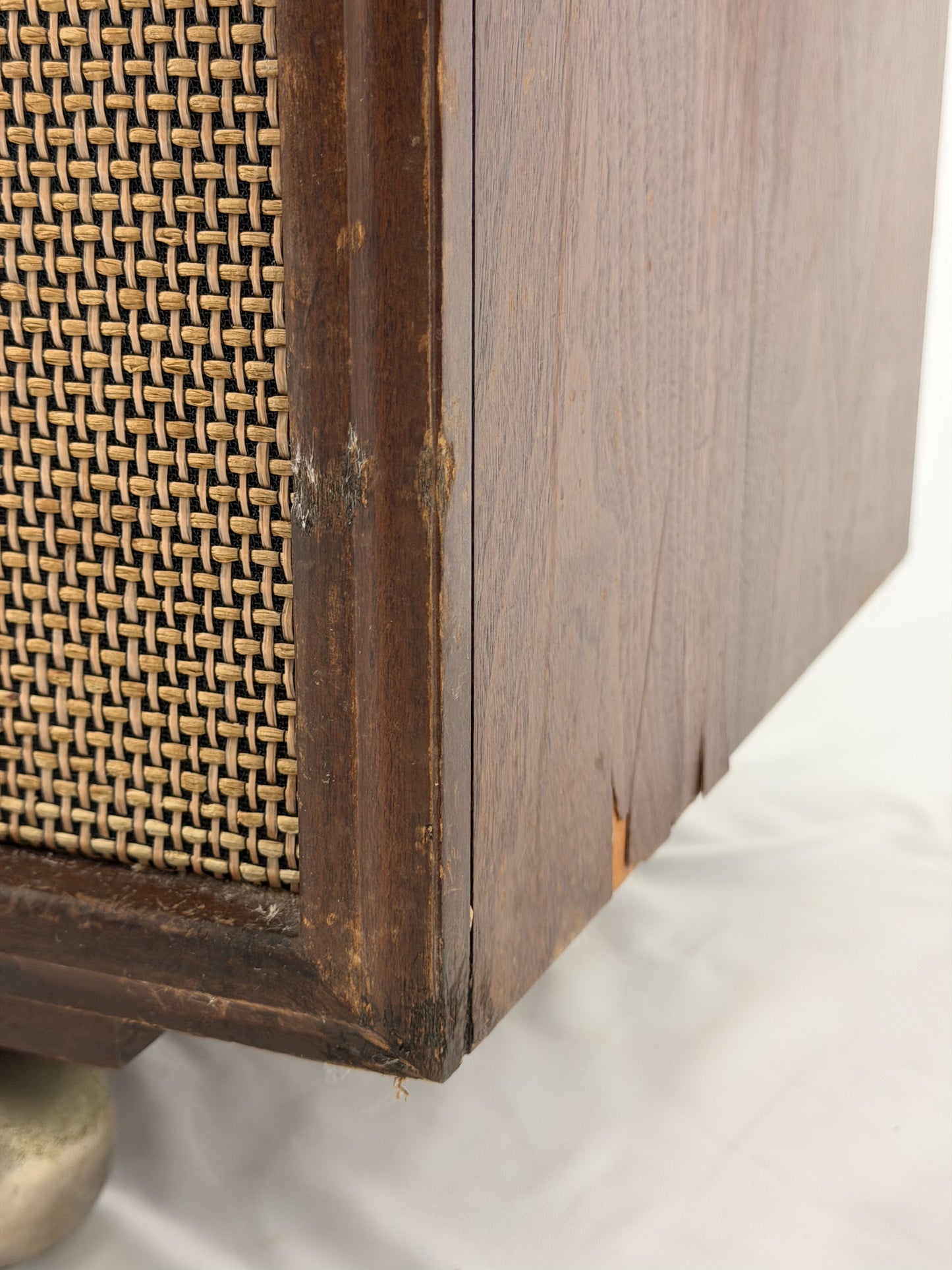 Close-up of a wooden cabinet with woven rattan side panel on a white background