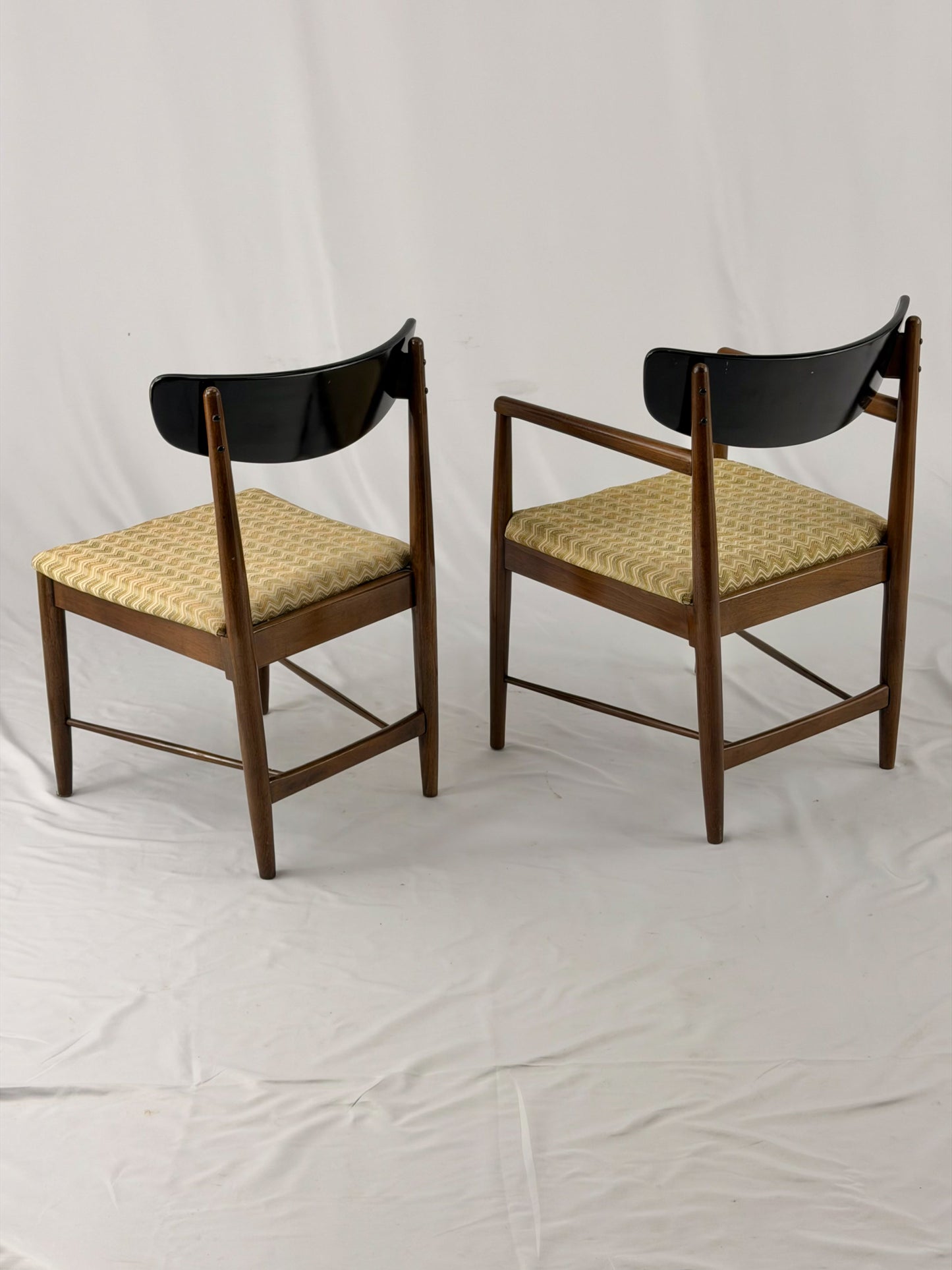 Two wooden chairs with upholstered seats on a white background