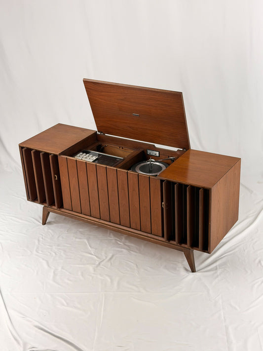 Vintage record player with a turntable and control panel on a wooden surface.