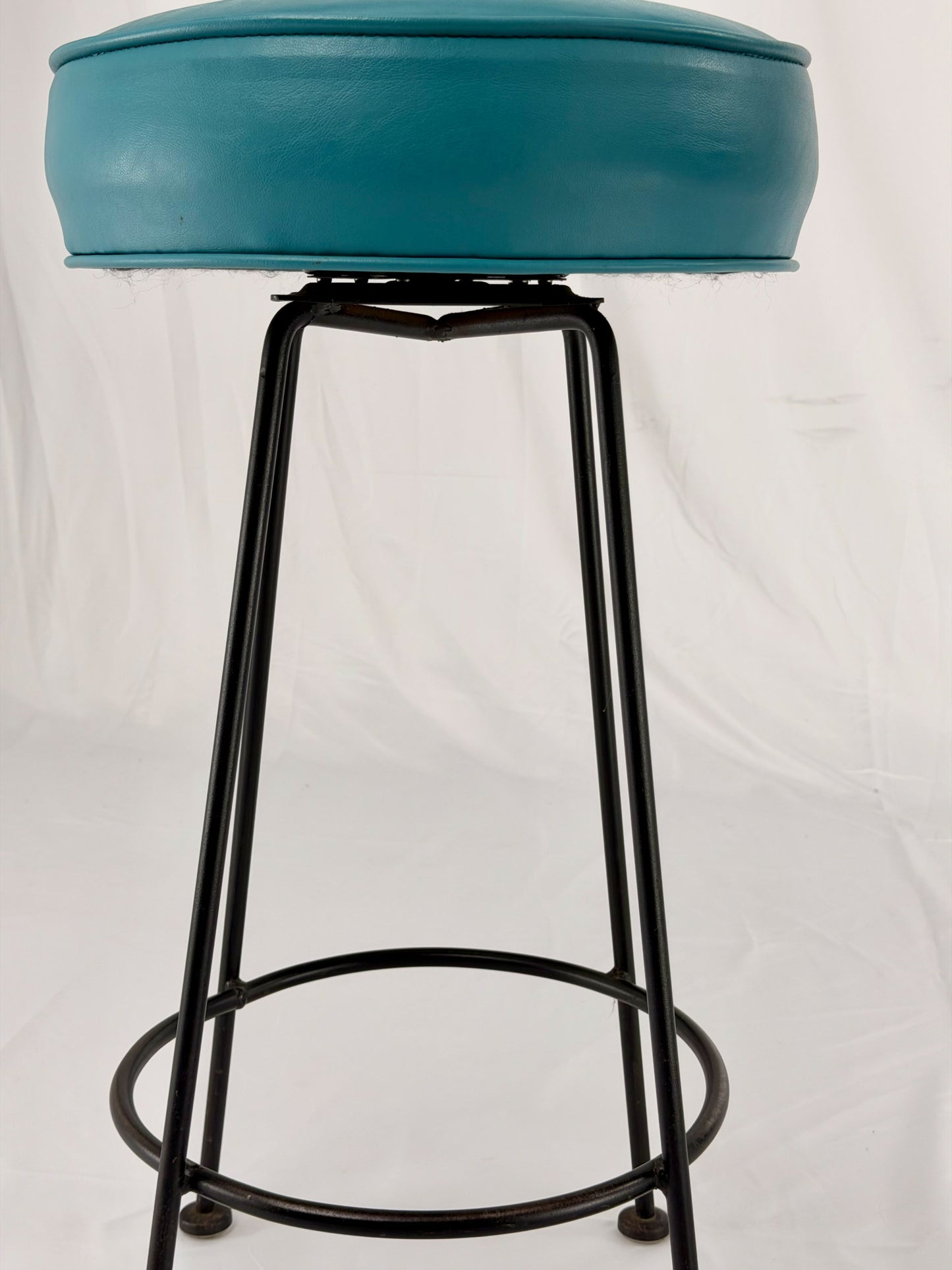Two teal bar stools with black metal legs on a white background