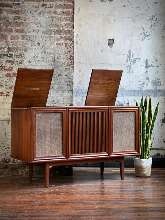 Wooden vintage stereo console in front of a textured brick wall