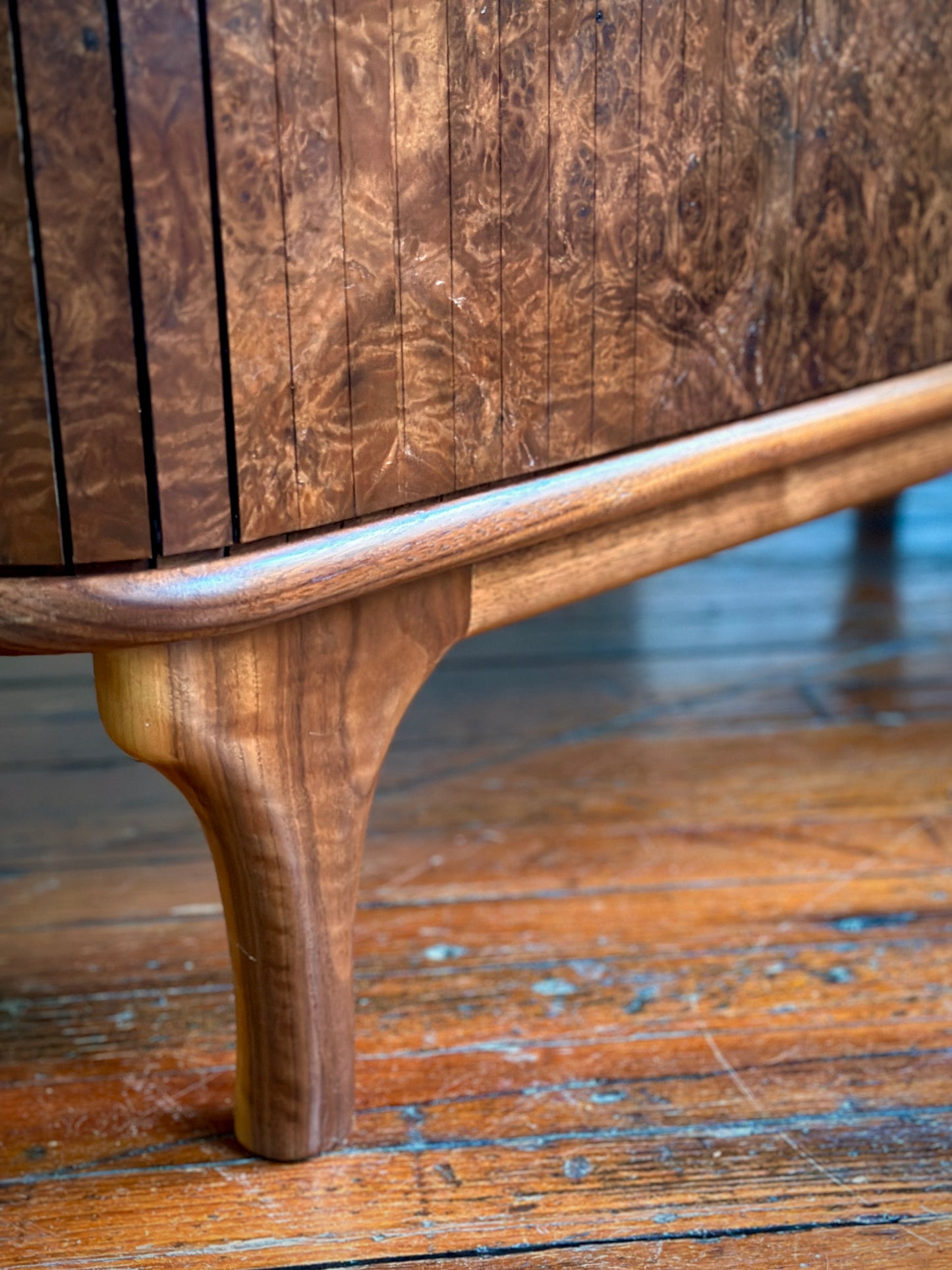 Close-up of a wooden cabinet leg on a wooden floor