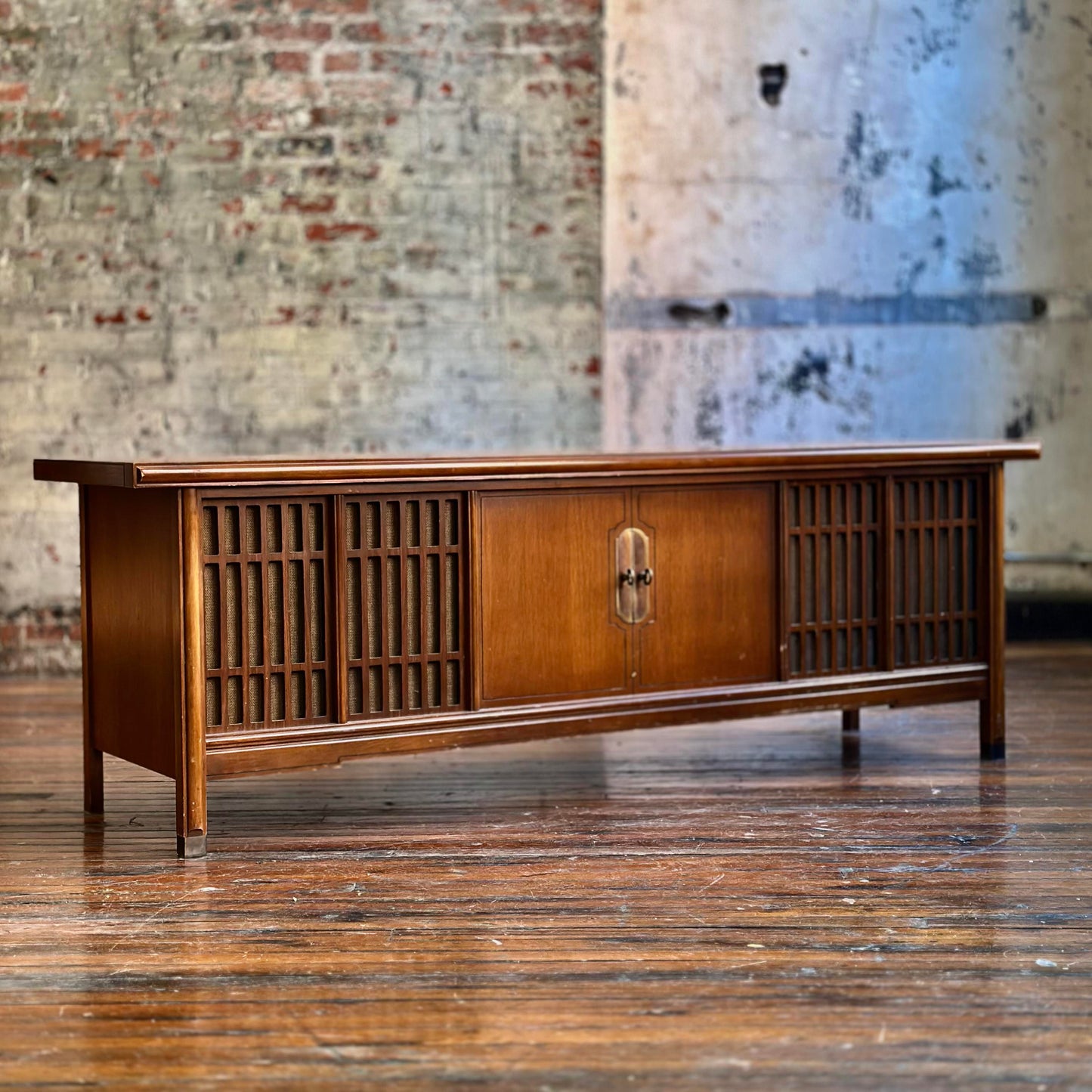 Wooden console with vintage radio against a rustic brick wall.