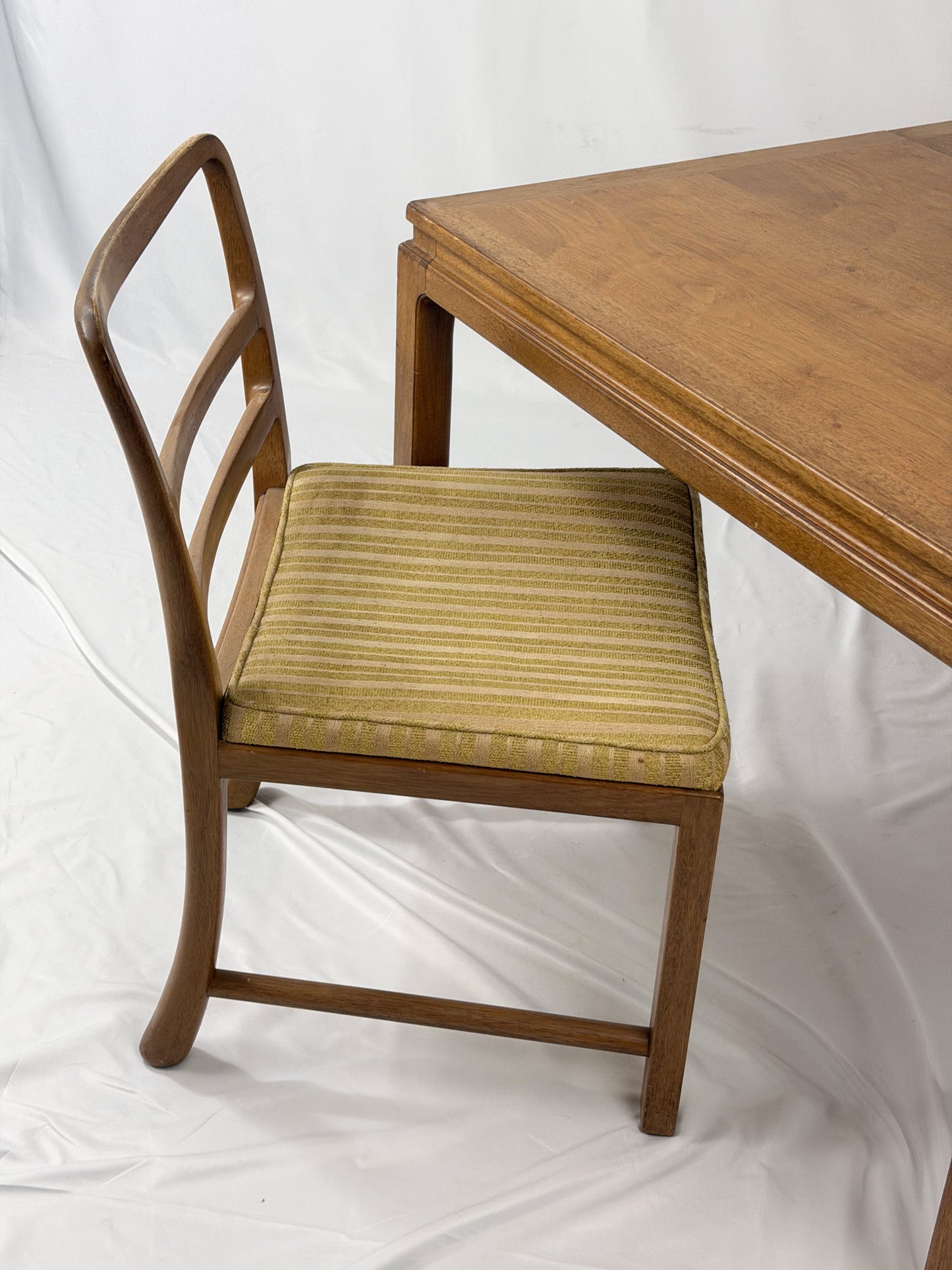 Wooden chair with striped cushion next to a wooden table on a white background