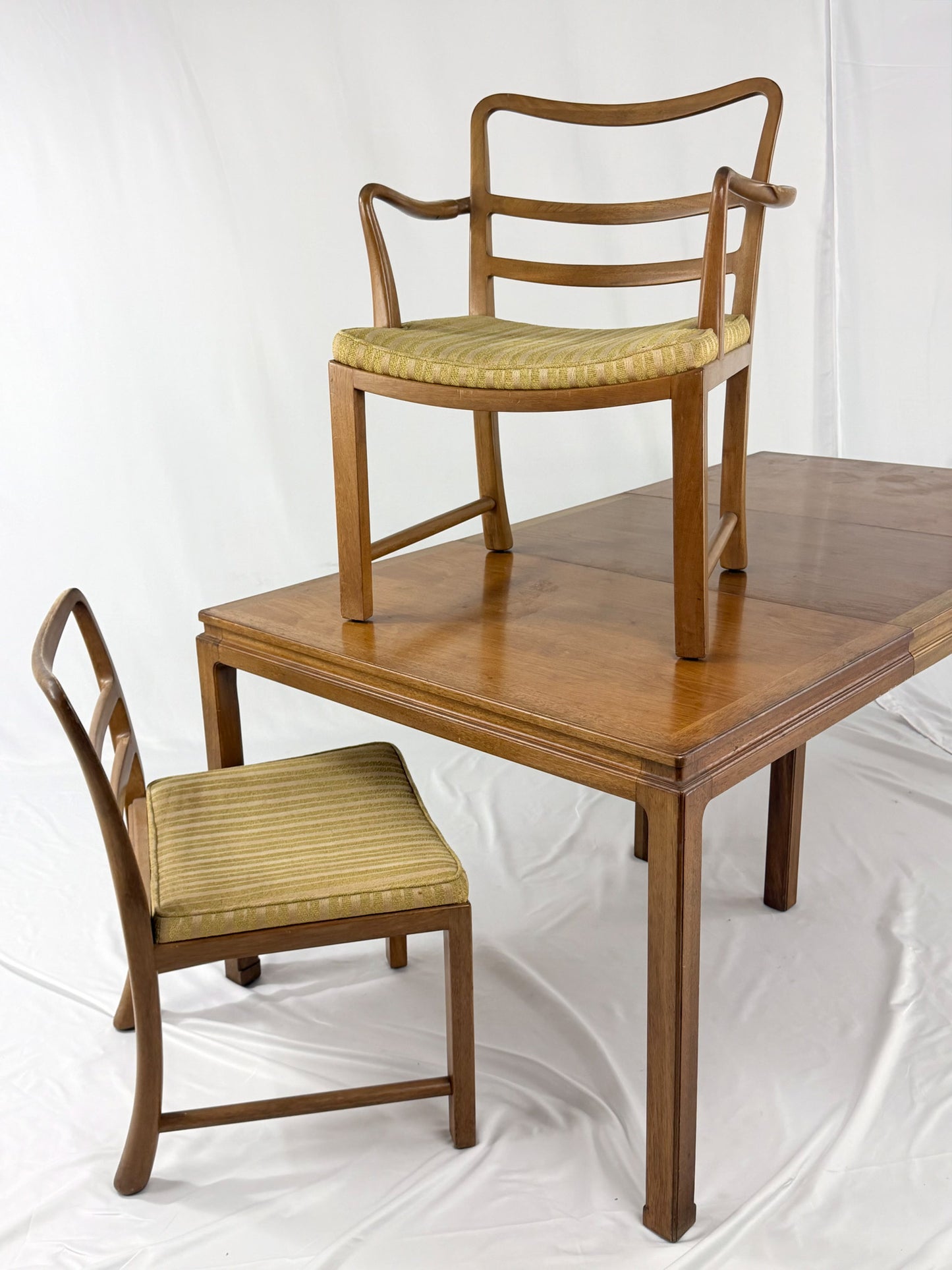 Wooden dining table with two matching chairs on a white background
