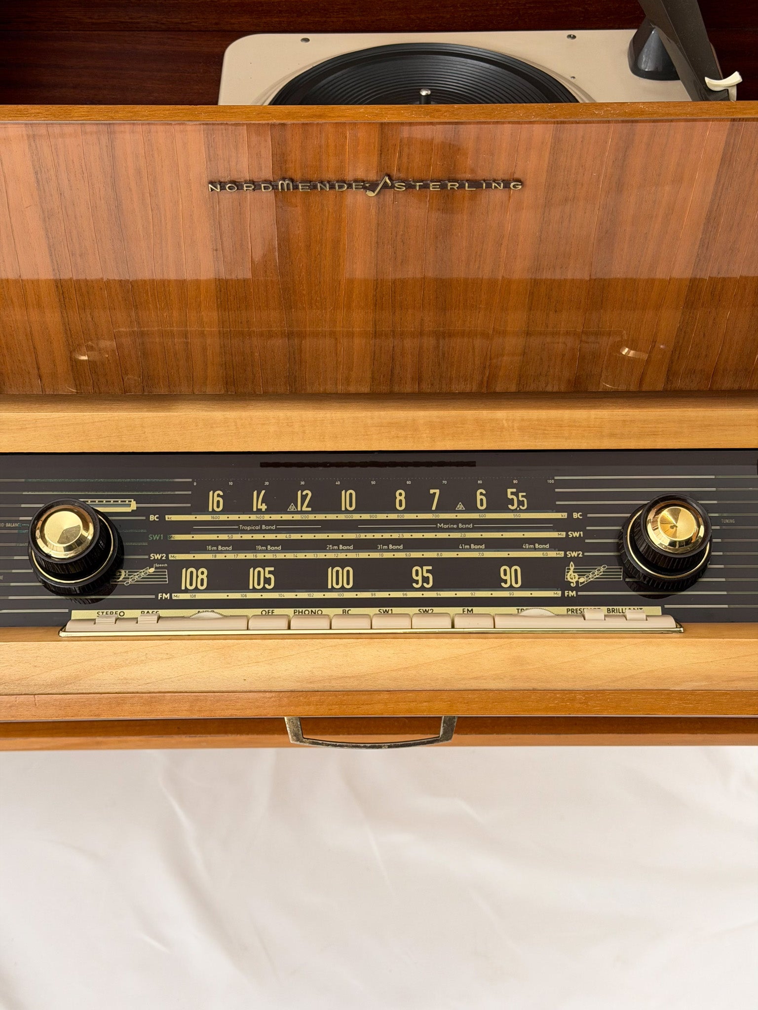 Vintage record player with a turntable and control panel on a wooden surface.