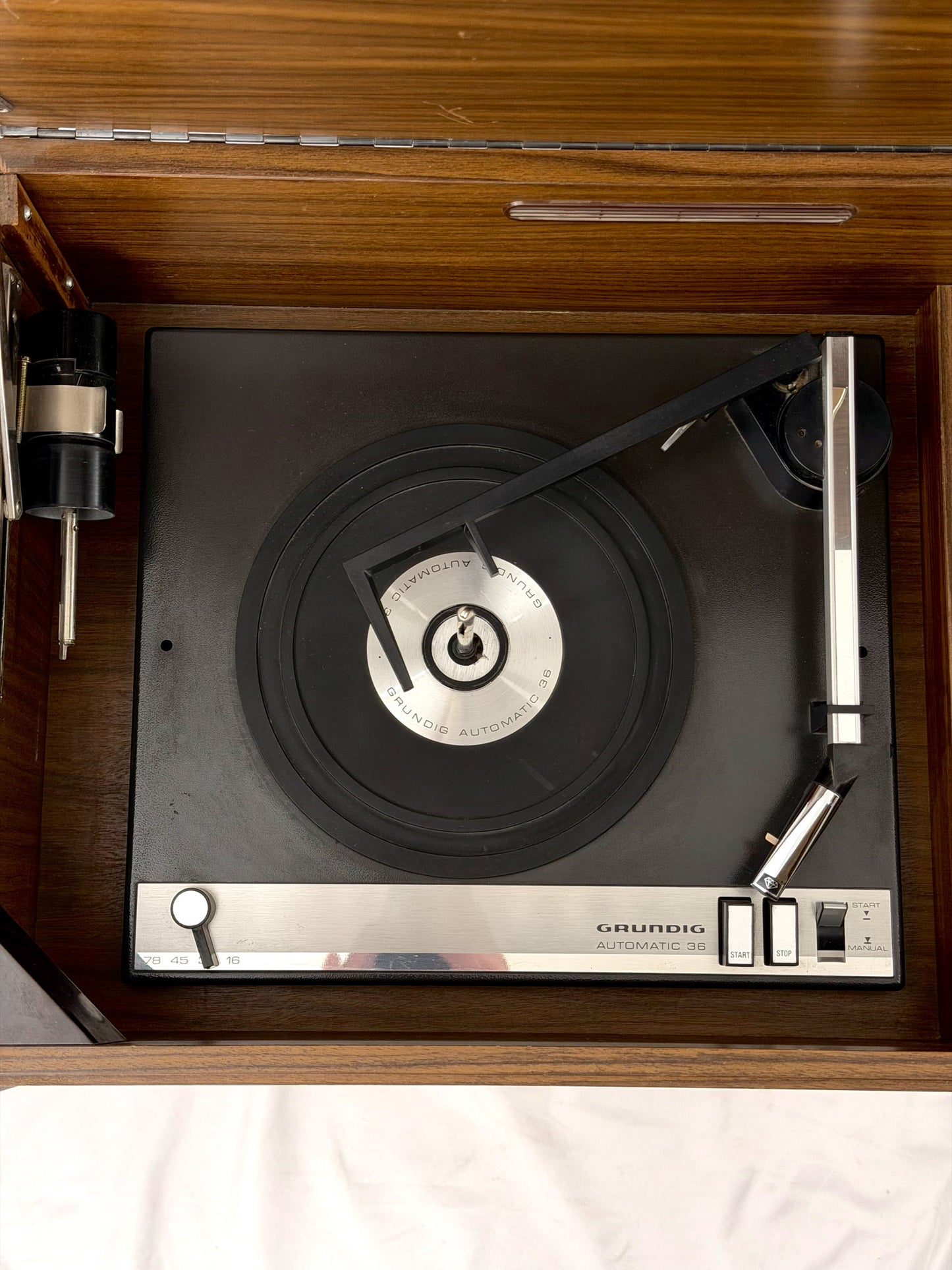 Vintage Grundig record player with a vinyl record on a wooden surface.