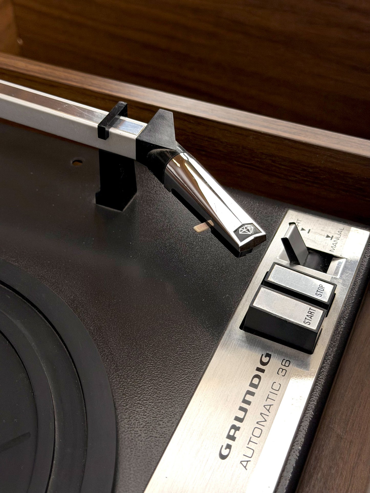 Close-up of a Grundig turntable with needle and control panel.