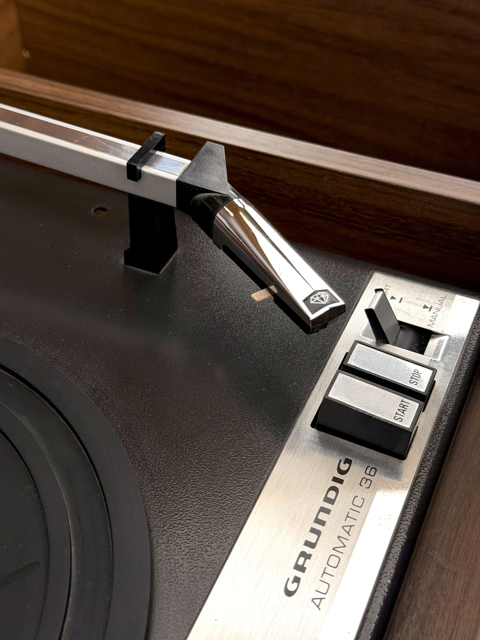 Close-up of a Grundig turntable with needle and control panel.