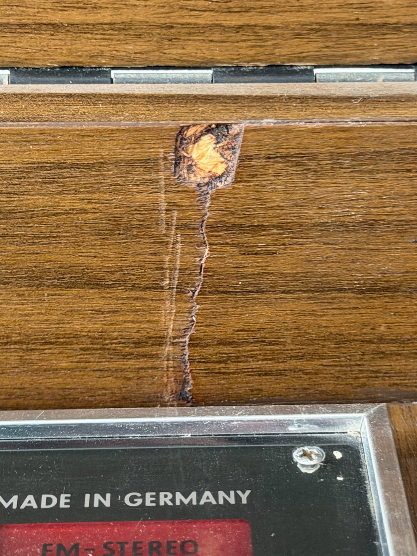 Close-up of a damaged cassette tape with a visible crack on a wooden surface, featuring 'Made in Germany' text.