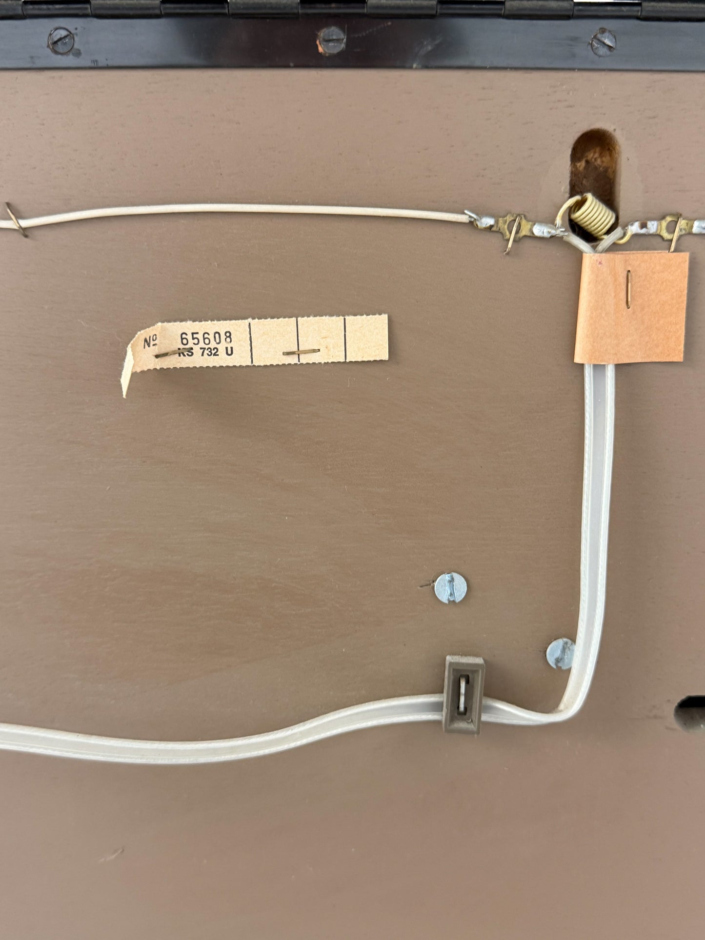 Close-up of a brown surface with electrical wiring and labels.