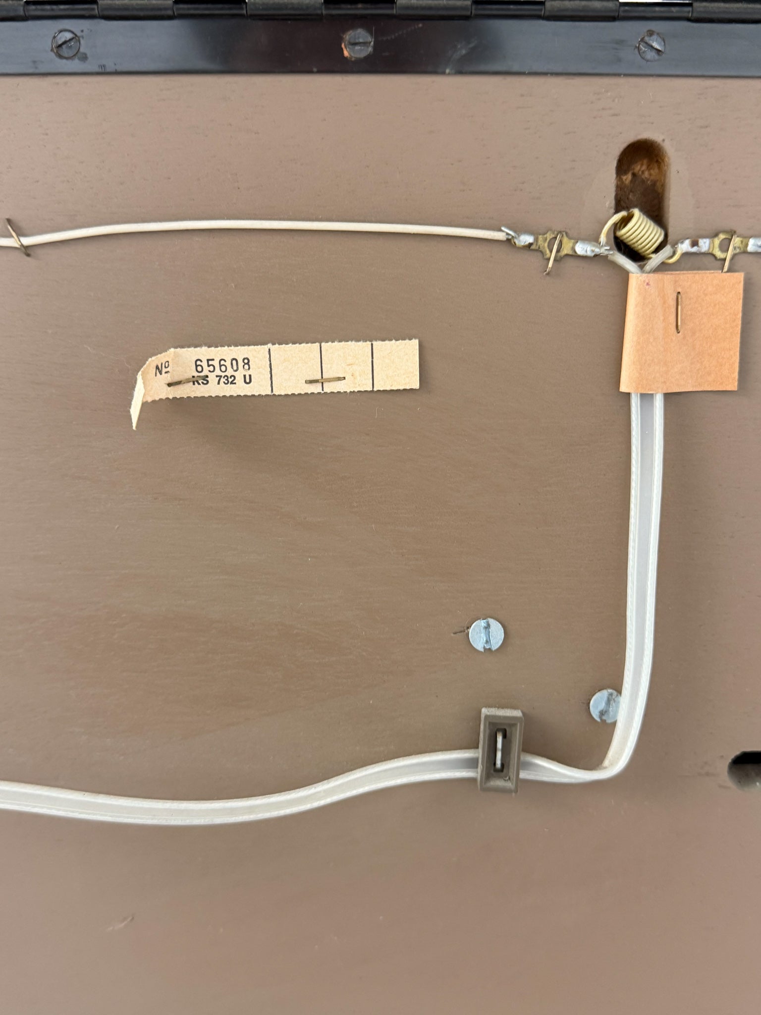 Close-up of a brown surface with electrical wiring and labels.