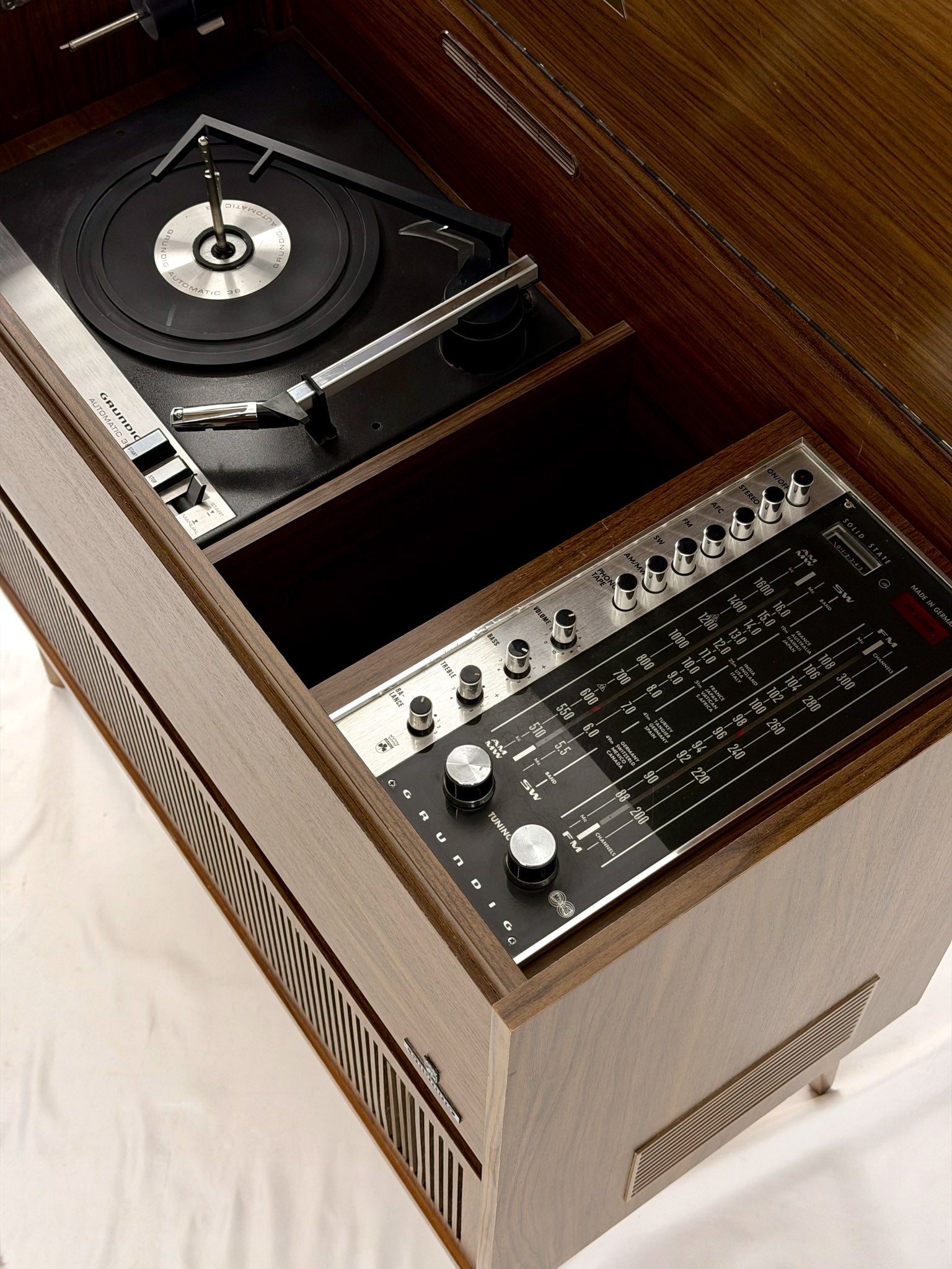 Vintage record player with a turntable and control panel on a wooden surface.