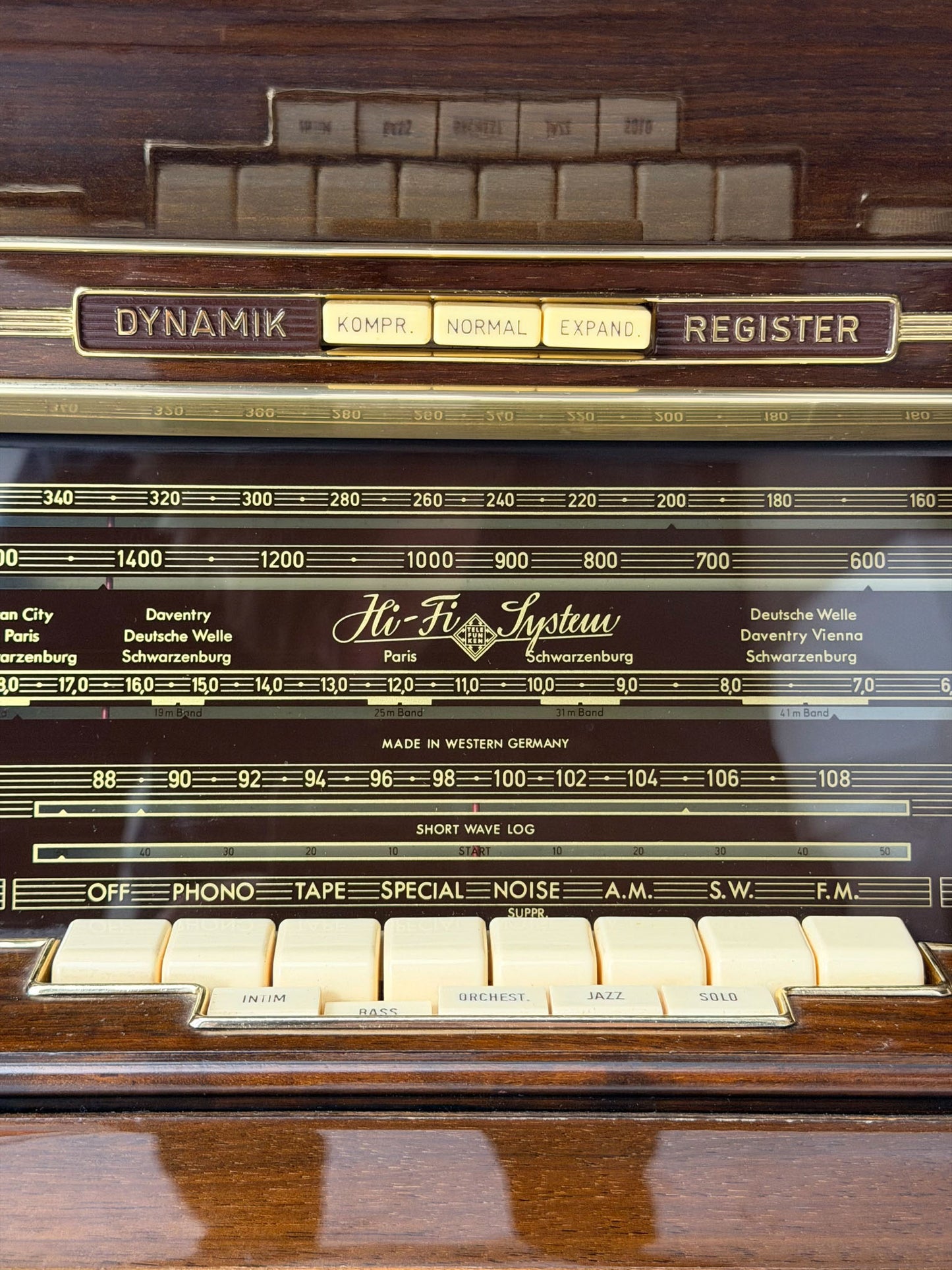 Vintage radio receiver with control knobs and brand name on a wooden surface
