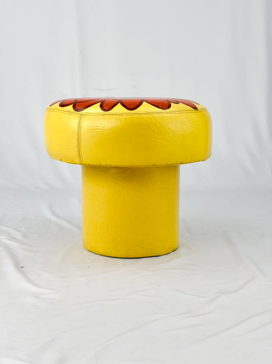 Yellow ottoman with a red floral design on a white background