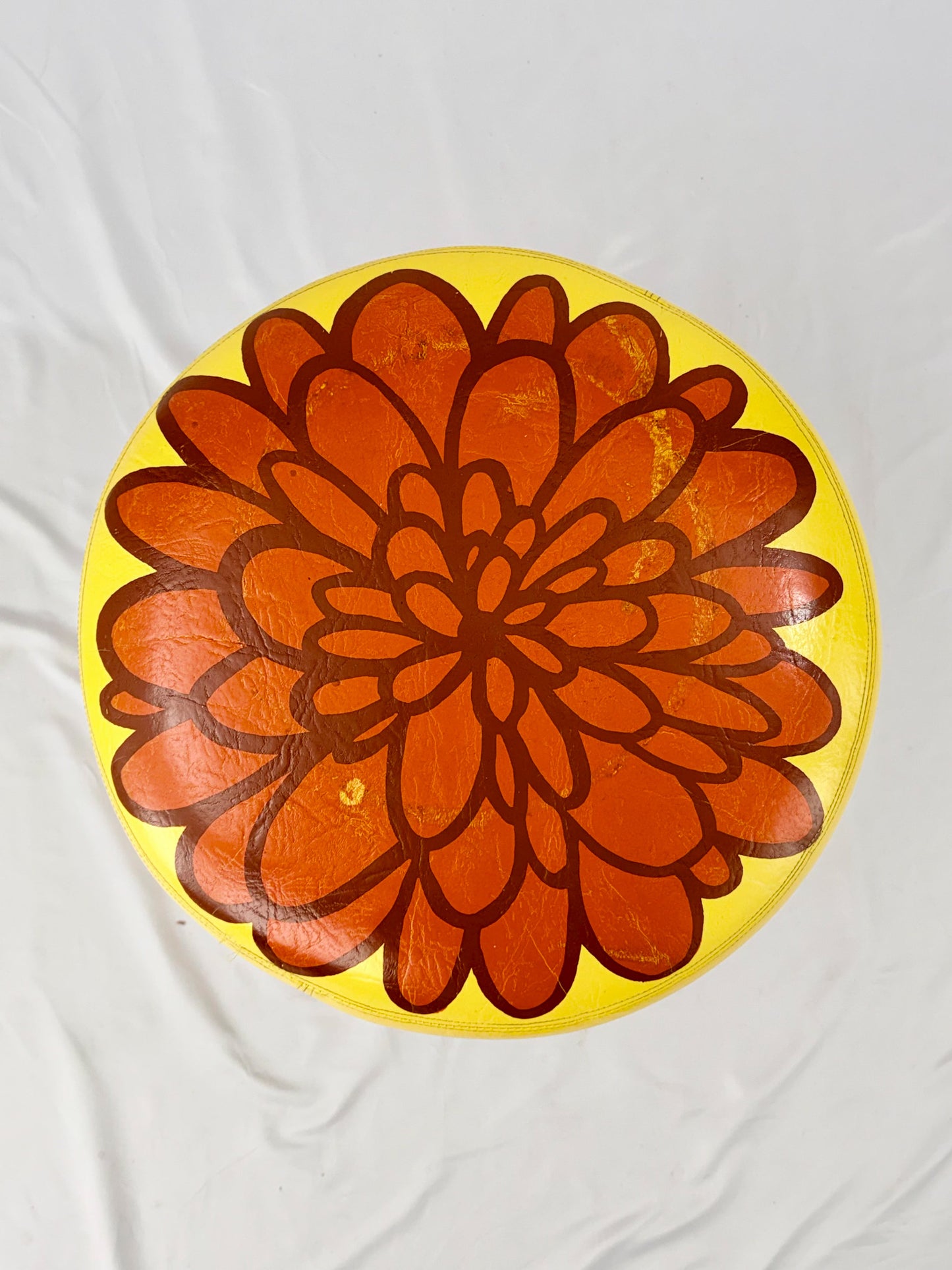 Yellow ottoman with a red floral design on a white background