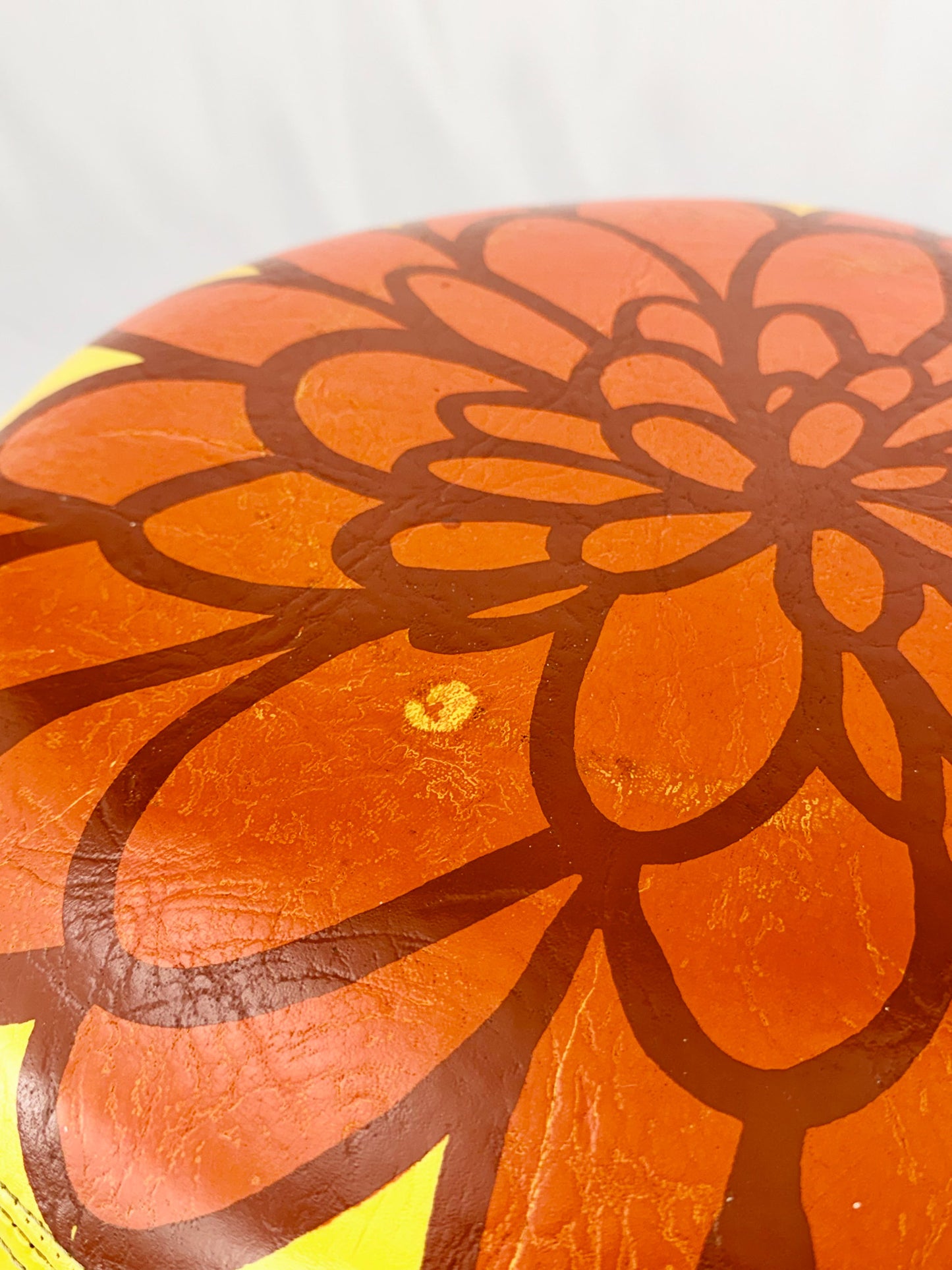 Yellow ottoman with a red floral design on a white background