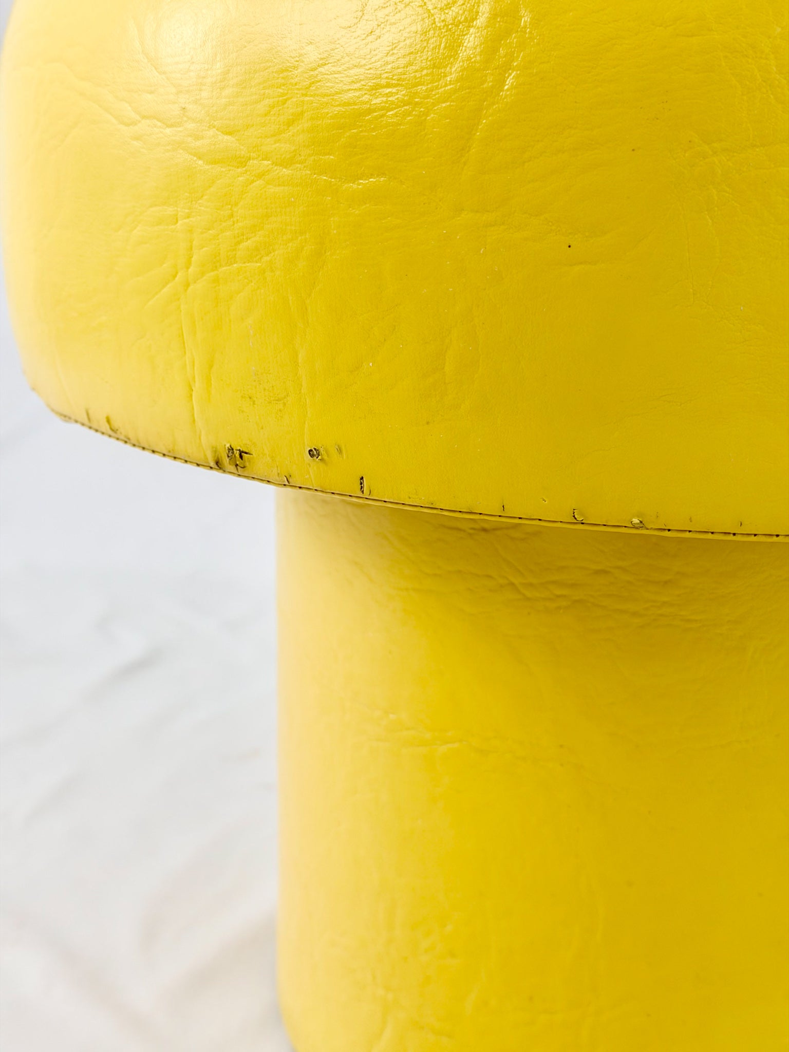 Yellow stool with a textured surface on a white background
