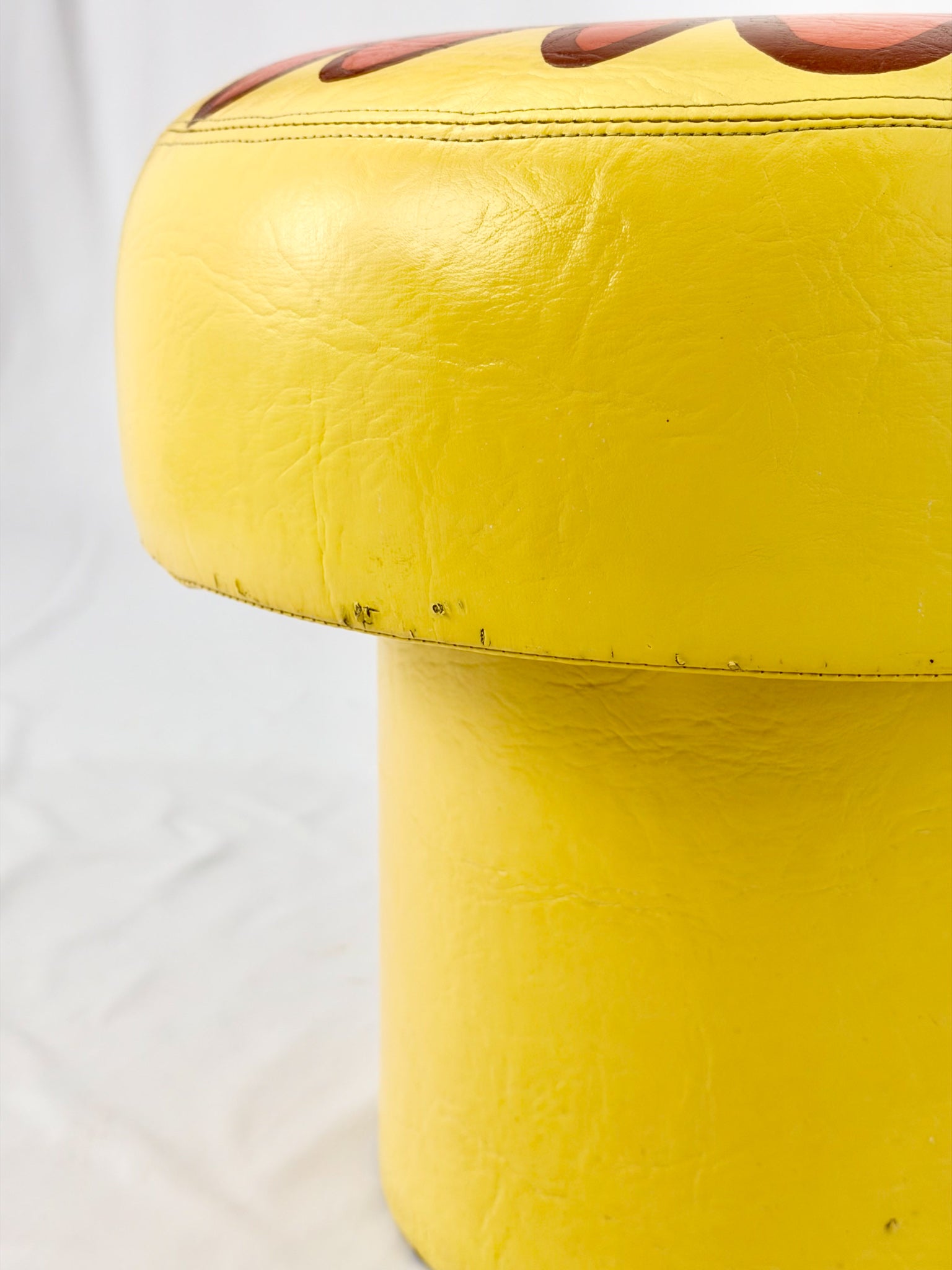 Yellow ottoman with a textured top on a white background