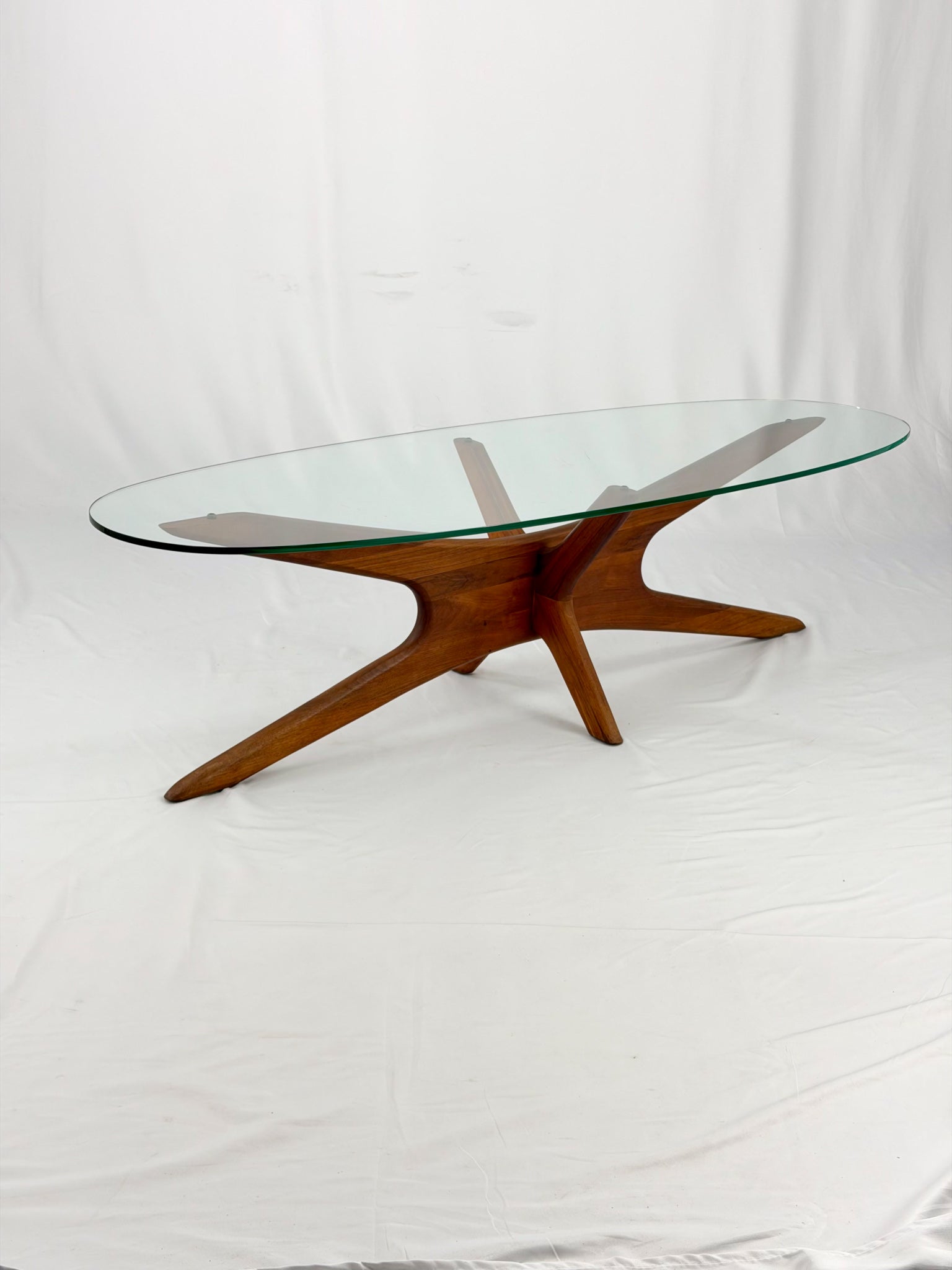 Glass-top coffee table with wooden starburst base on a white background
