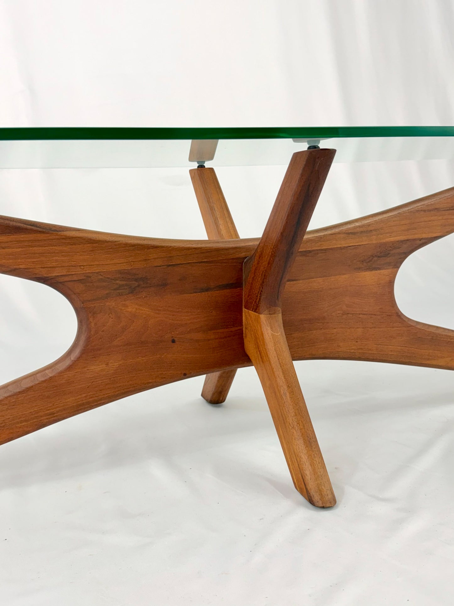 Glass-top table with wooden base on a white background