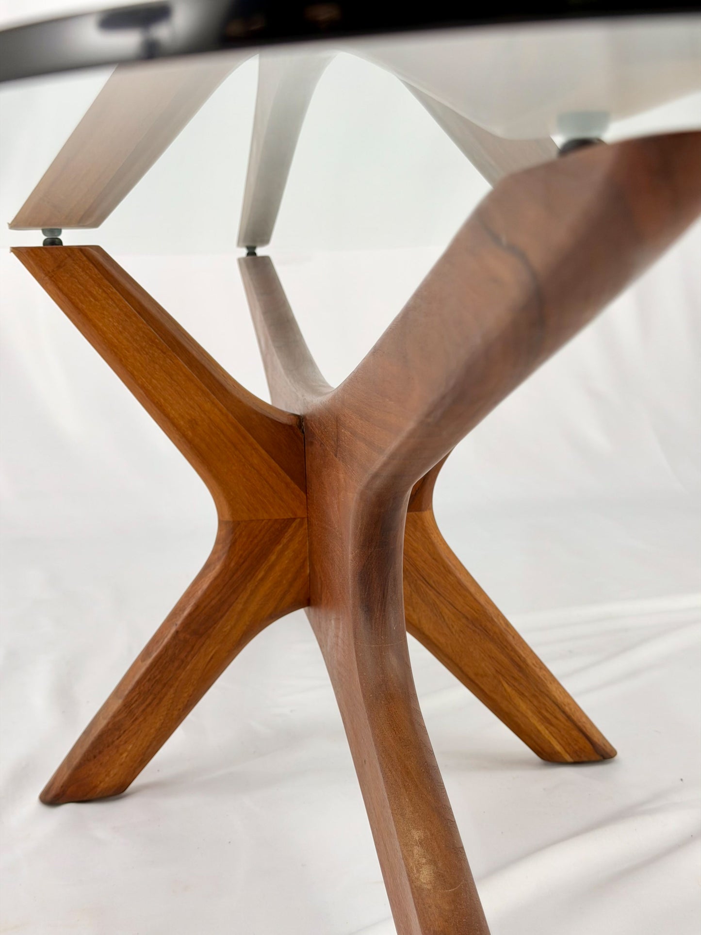 Glass-top table with wooden base on a white background