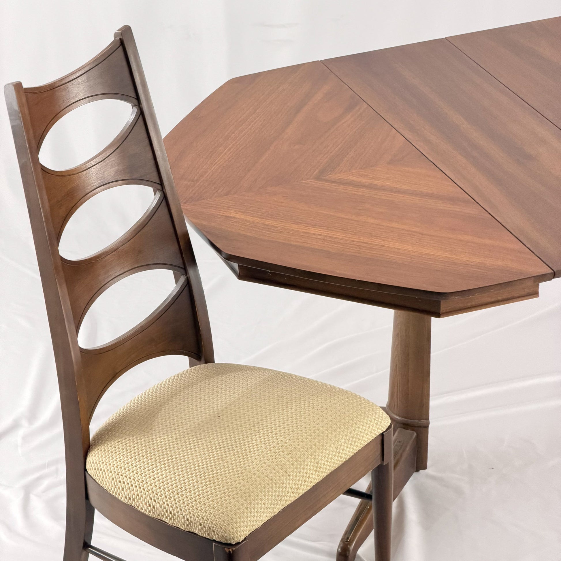 Wooden chair with a beige cushion next to a wooden table on a white background