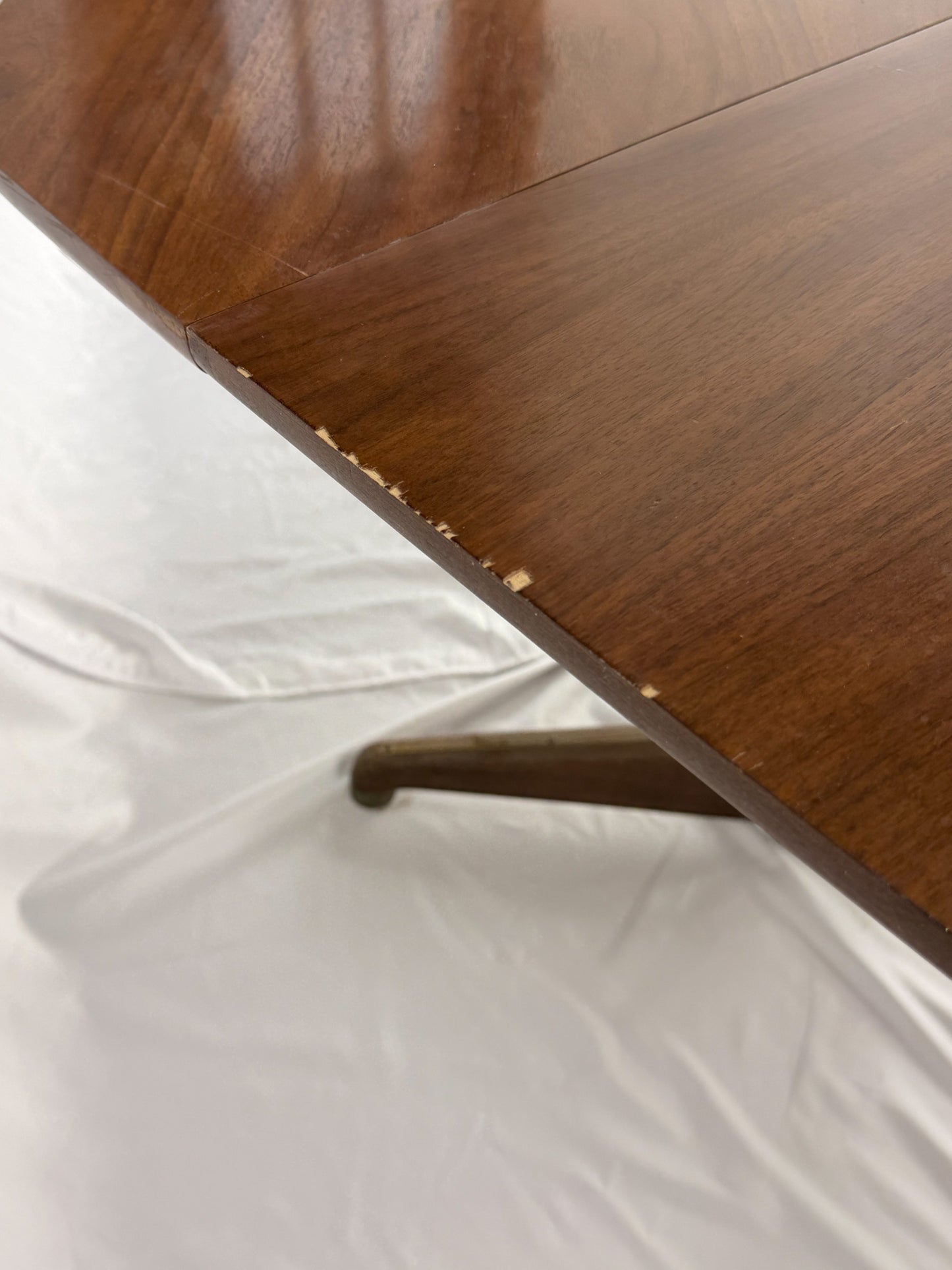 Close-up of a wooden table corner with a white fabric surface underneath