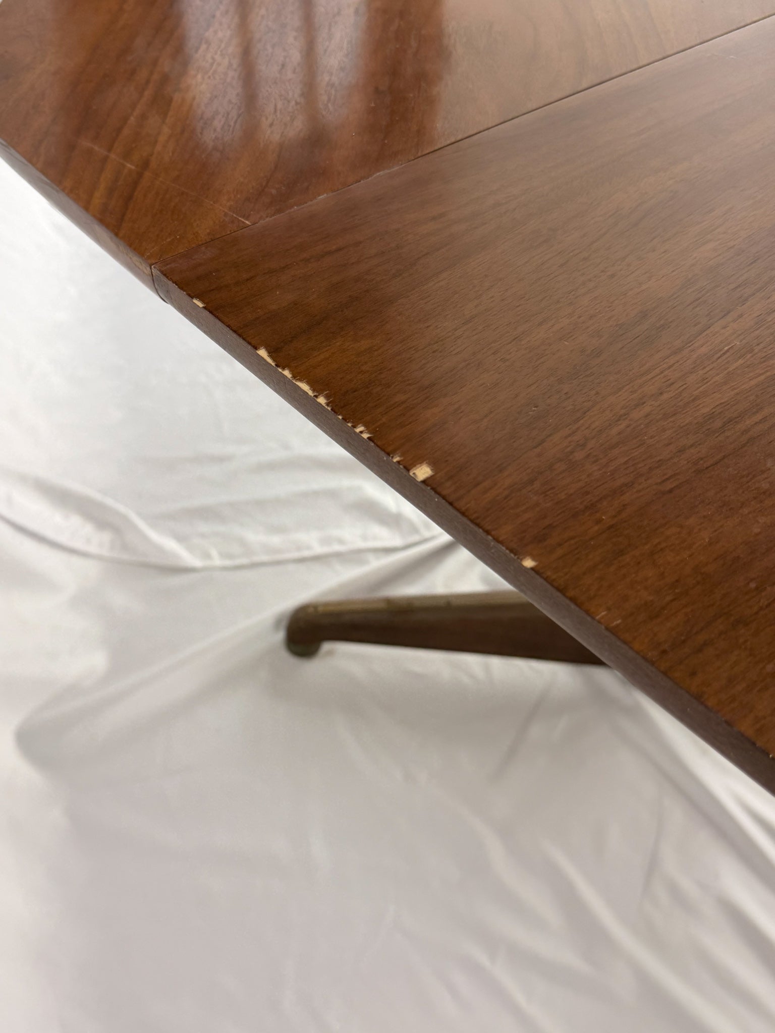 Close-up of a wooden table corner with a white fabric surface underneath