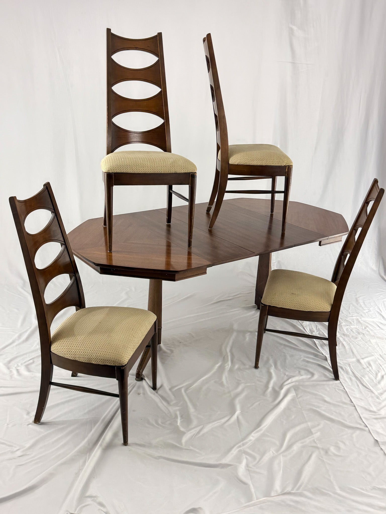 Wooden dining table with four matching chairs on a textured white background