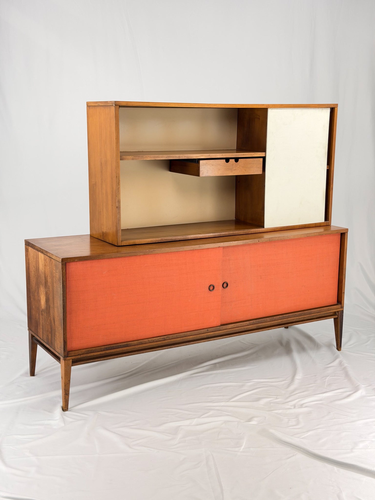 Wooden entertainment console with orange cabinet and open shelf on a white background