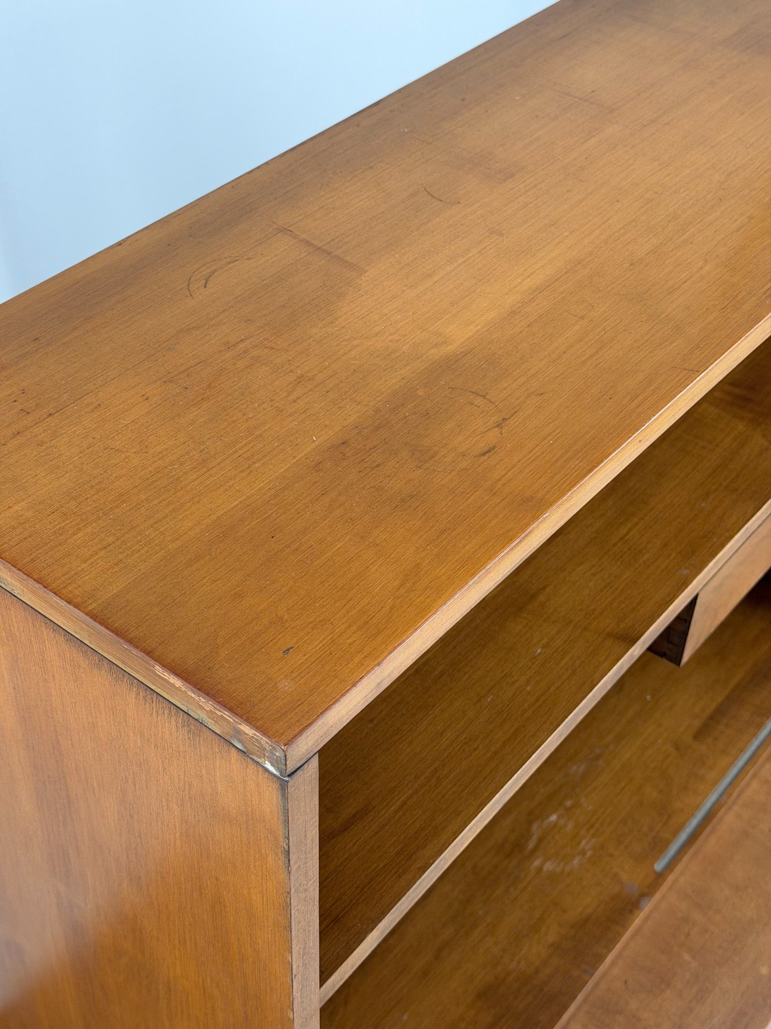 Wooden entertainment console with orange cabinet and open shelf on a white background
