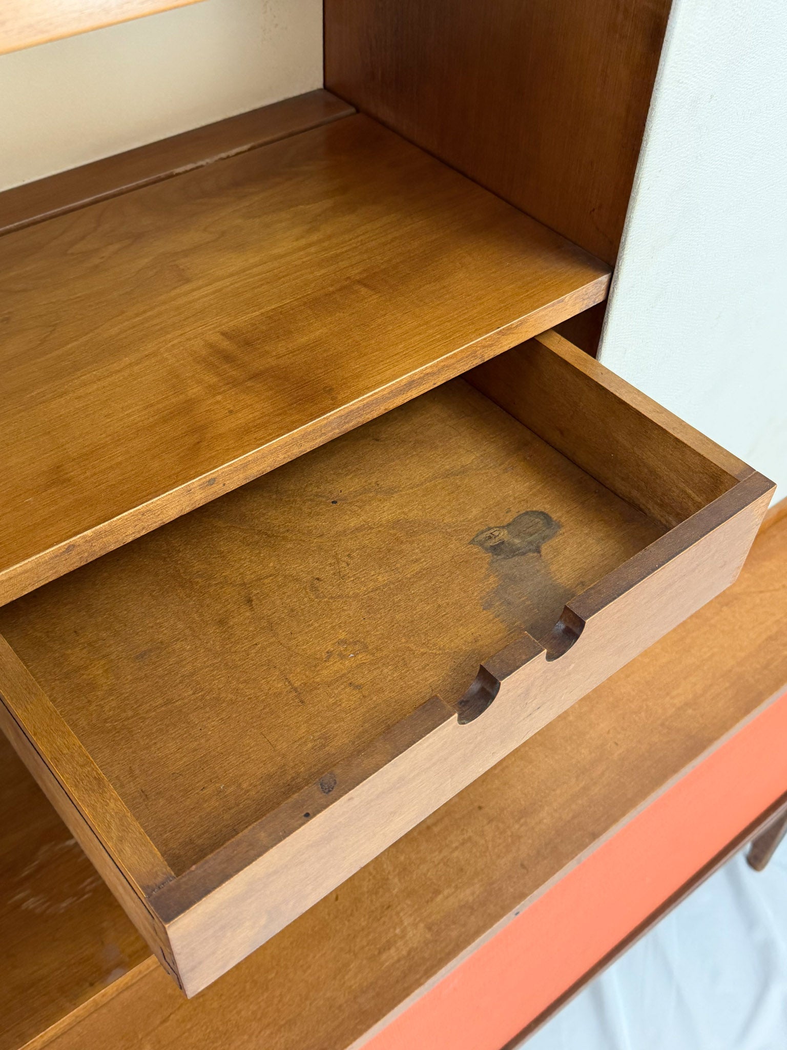 Wooden entertainment console with orange cabinet and open shelf on a white background