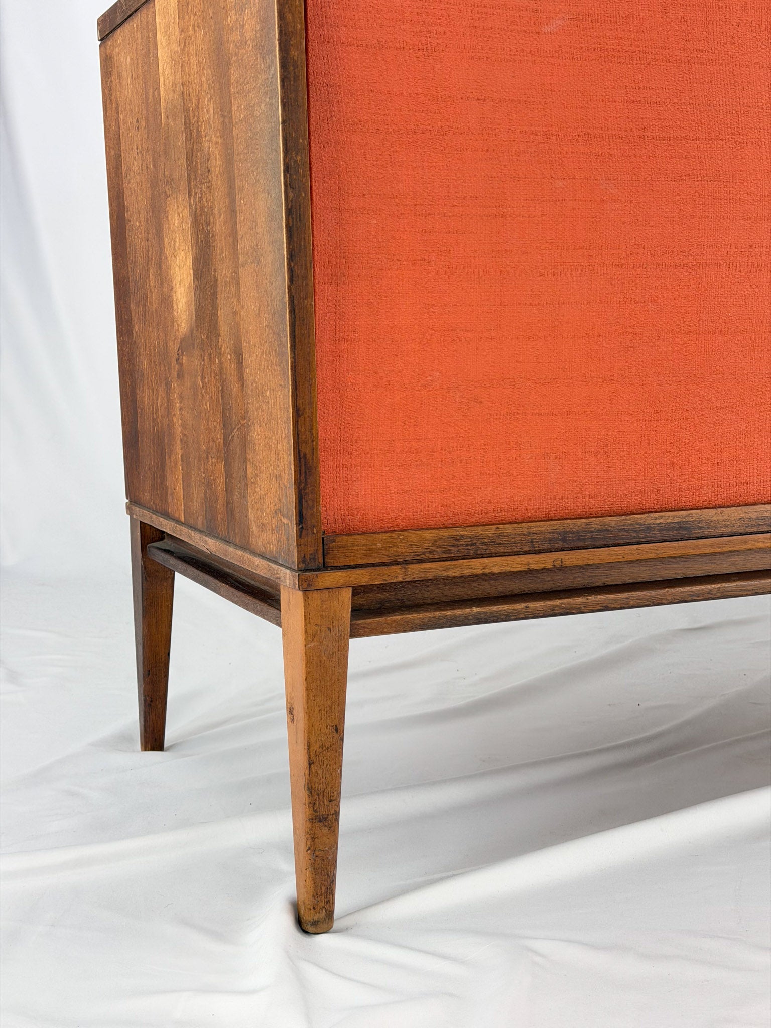 Wooden entertainment console with orange cabinet and open shelf on a white background