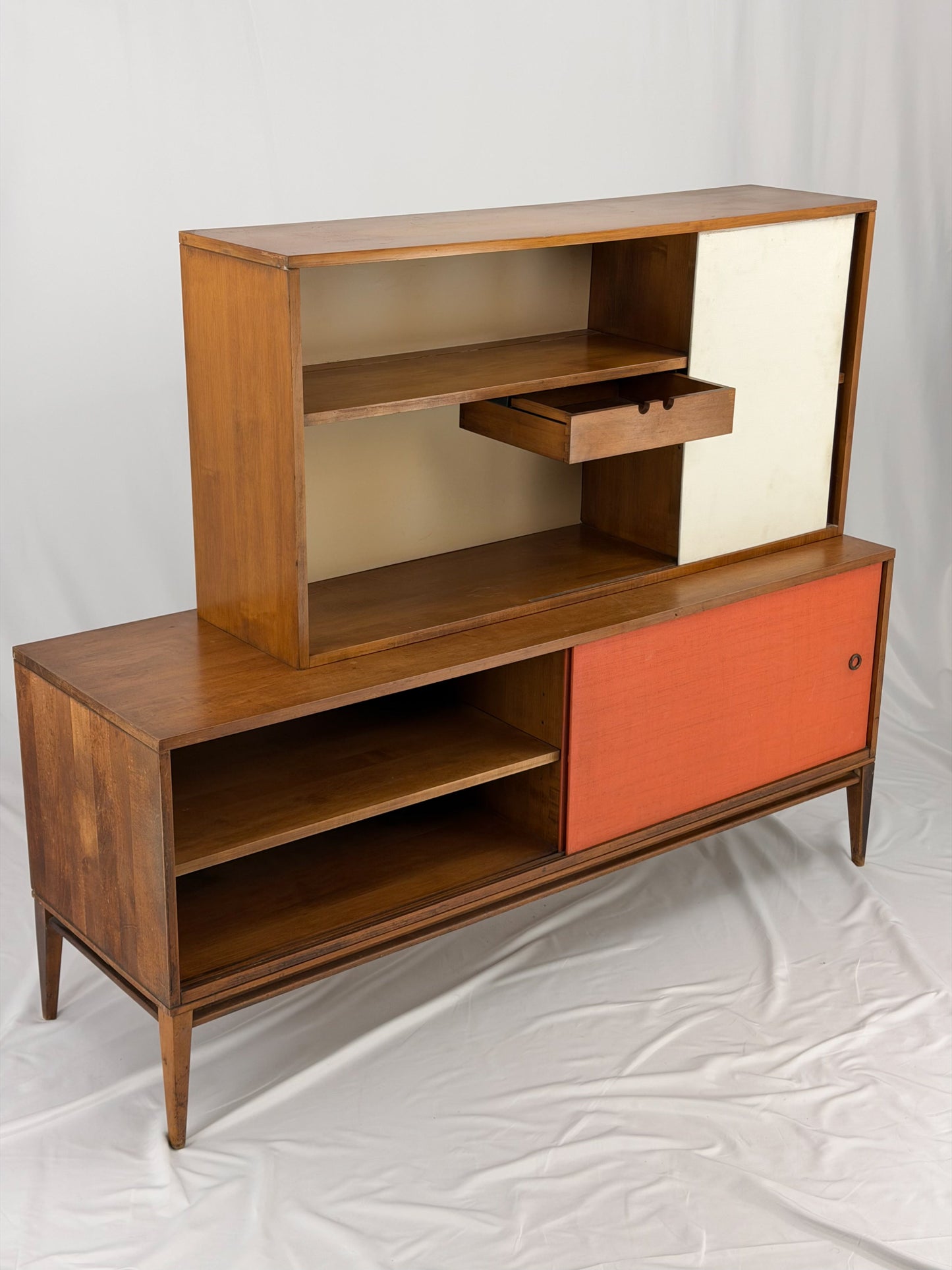 Wooden entertainment console with orange cabinet and open shelf on a white background