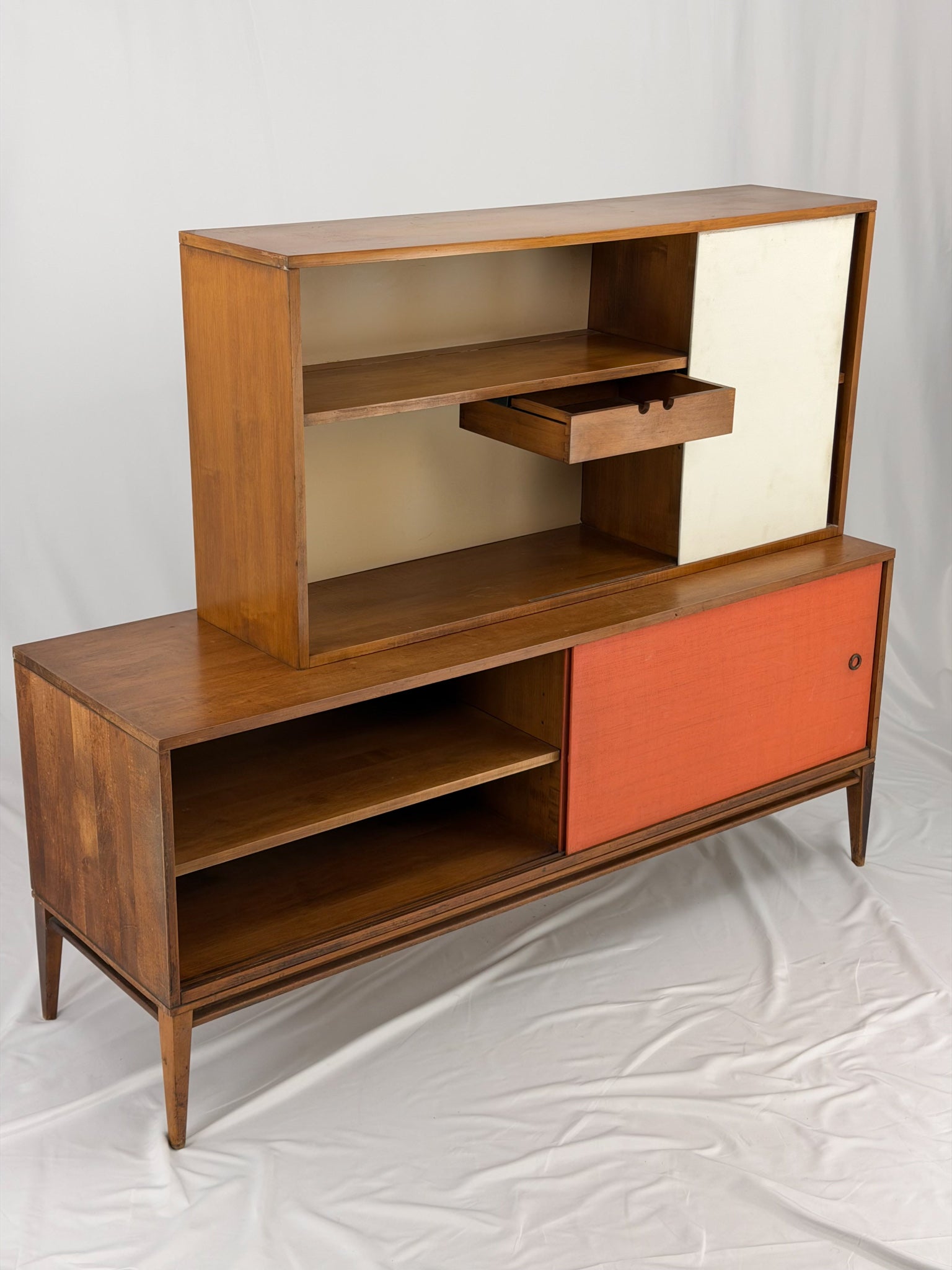 Wooden entertainment console with orange cabinet and open shelf on a white background