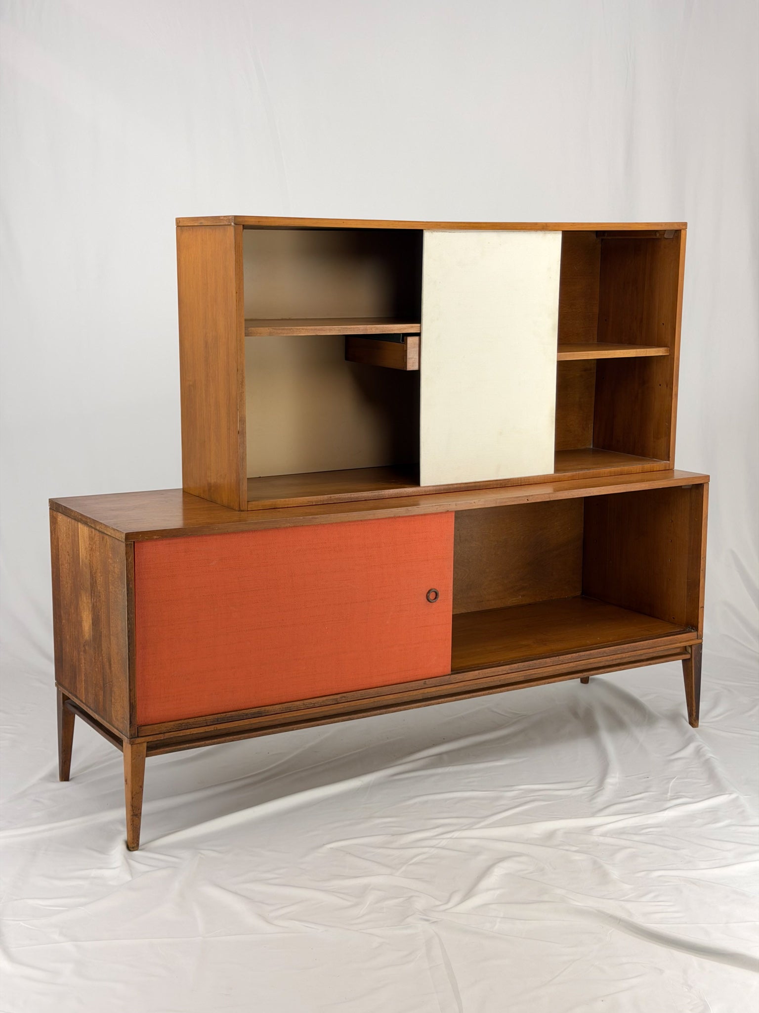 Wooden entertainment console with orange cabinet and open shelf on a white background