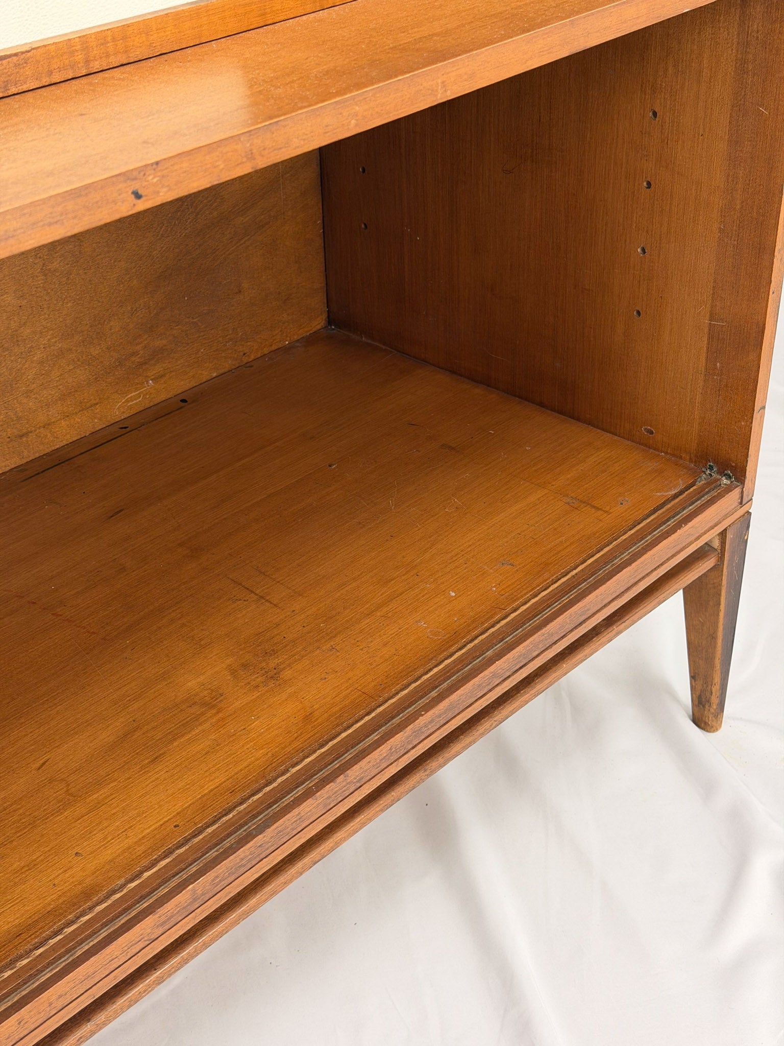 Wooden entertainment console with orange cabinet and open shelf on a white background