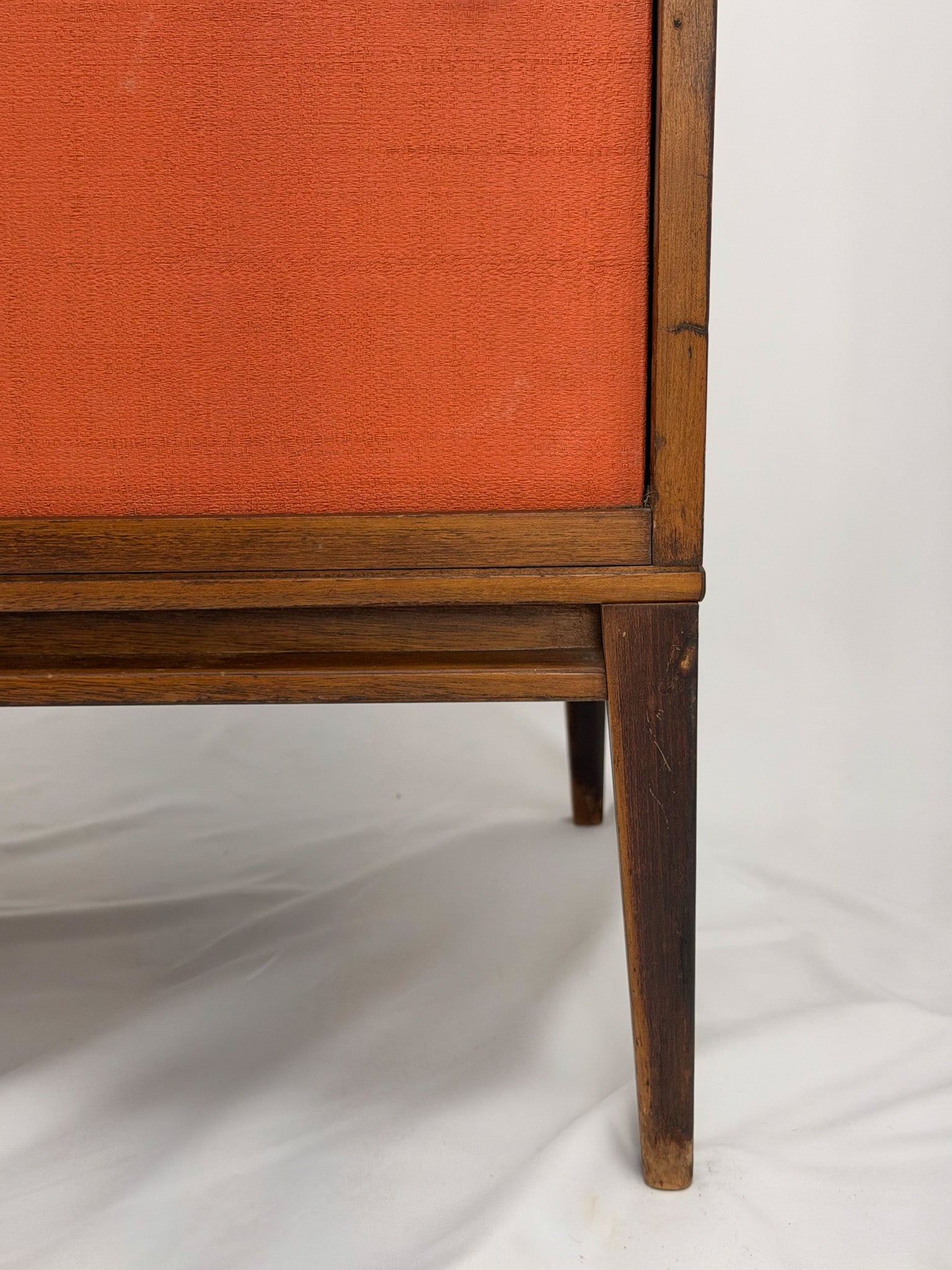 Wooden entertainment console with orange cabinet and open shelf on a white background