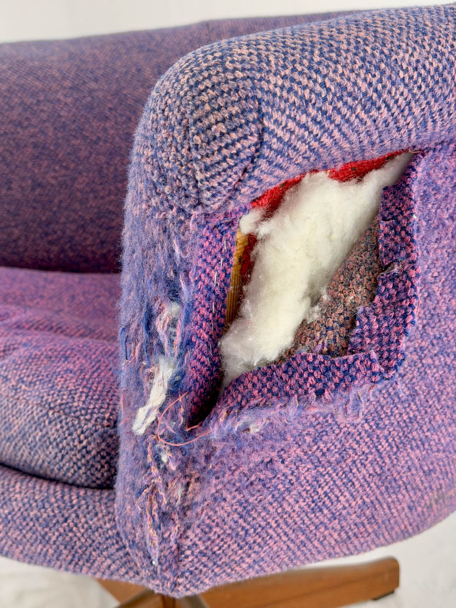 Purple upholstered chair with a hole exposing white stuffing