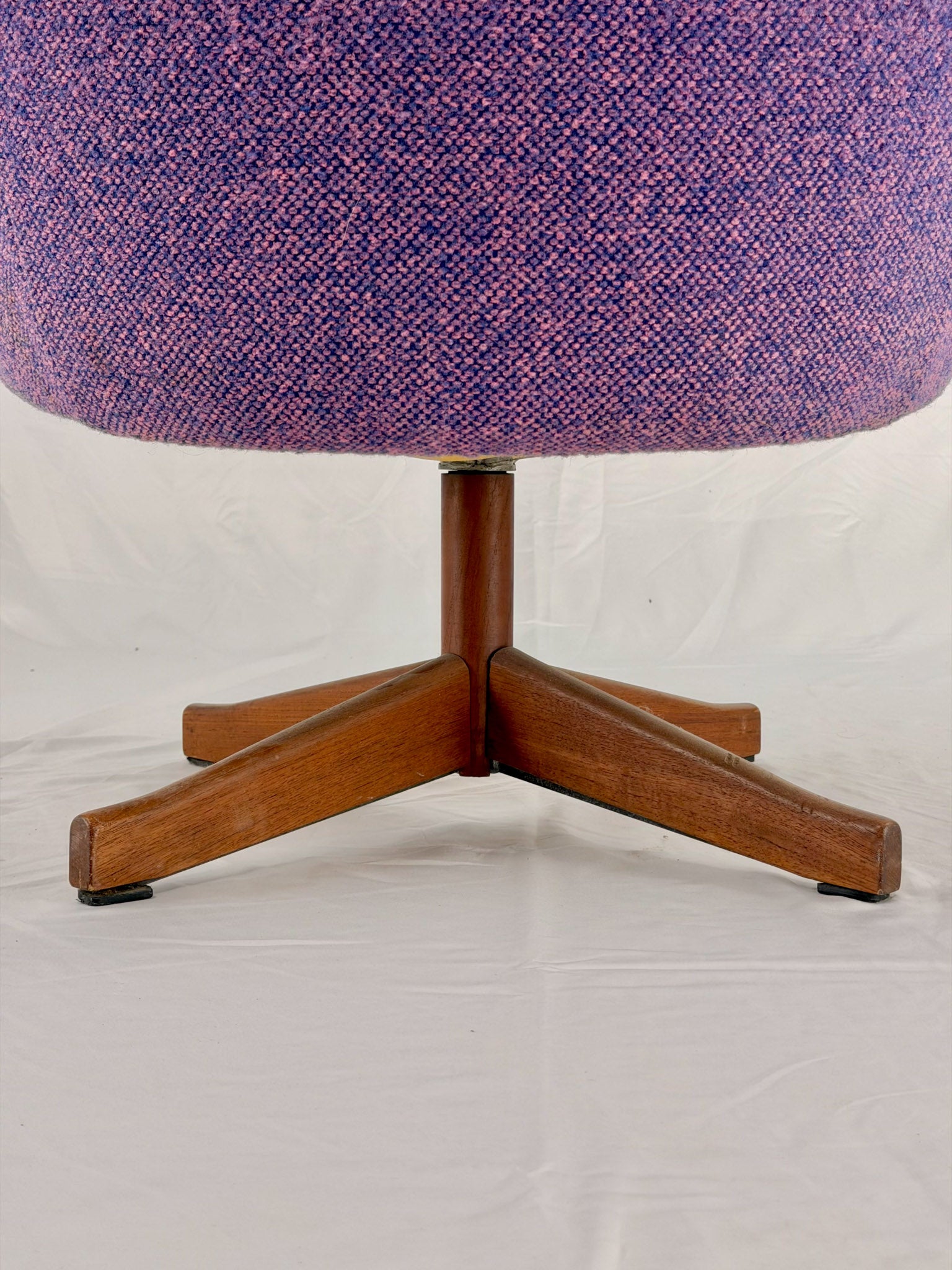 Close-up of a chair with a purple upholstered seat and wooden base on a white background