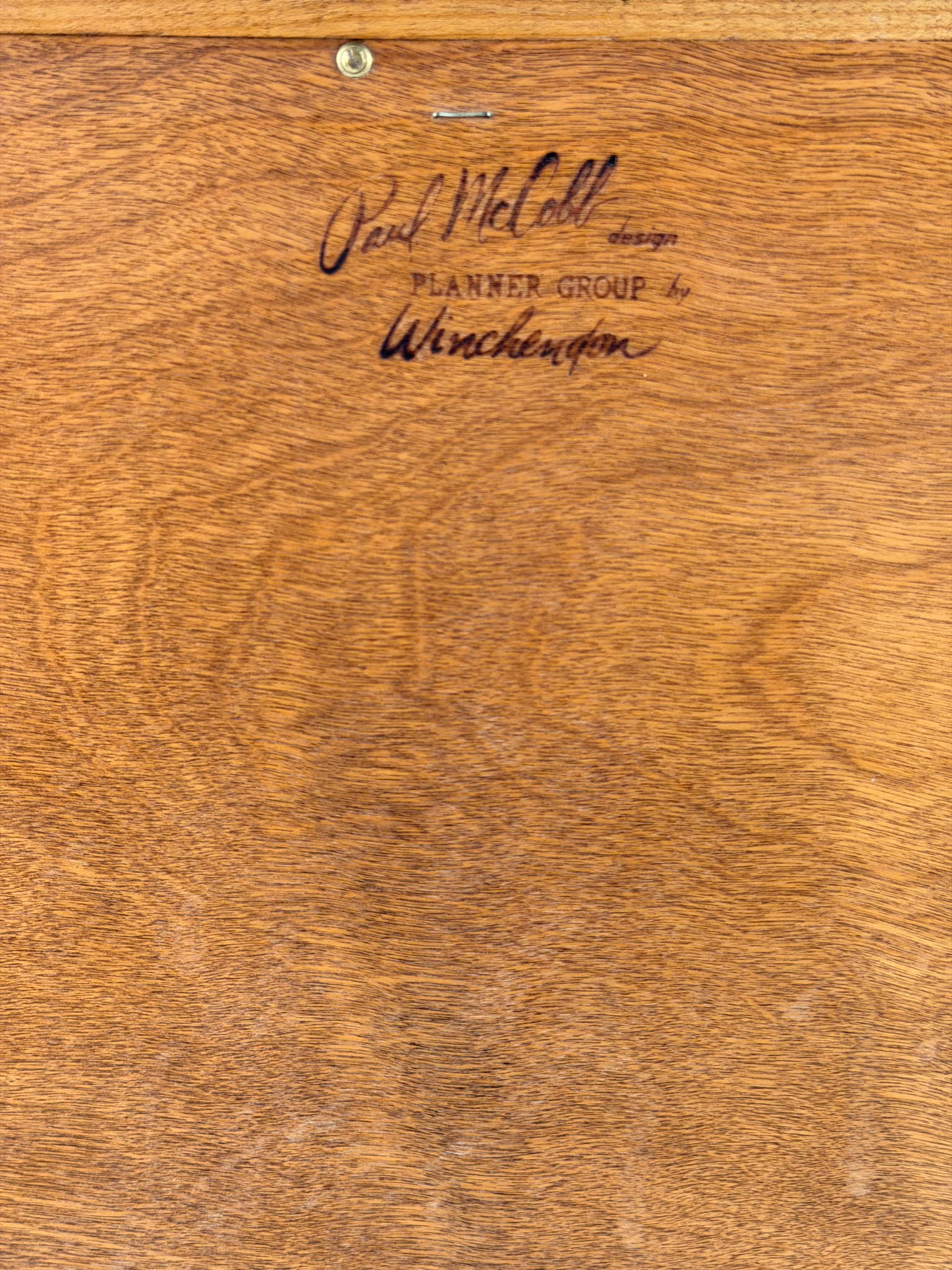 Wooden surface with engraved text 'Paul McCobb designs Planner Group by Winchester'