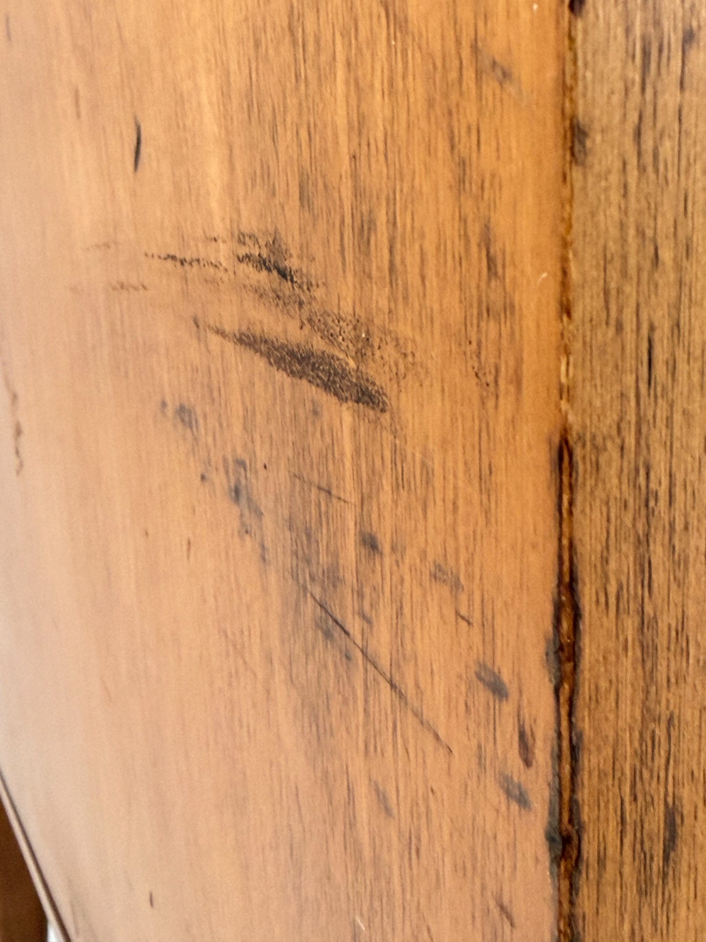 Close-up of a wooden surface with dark stains and a visible crack.