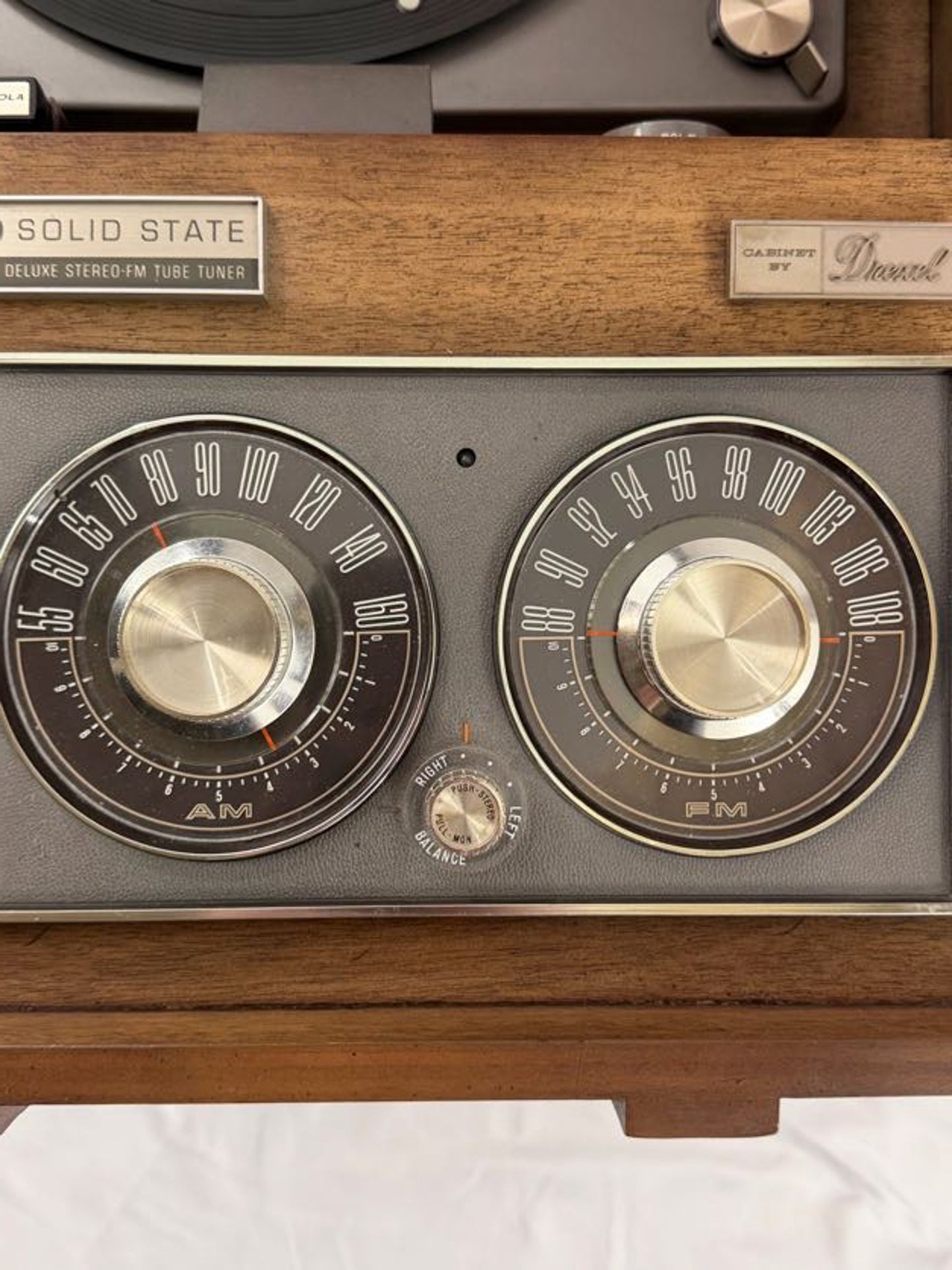 Vintage radio with wooden casing and metallic knobs on a white background