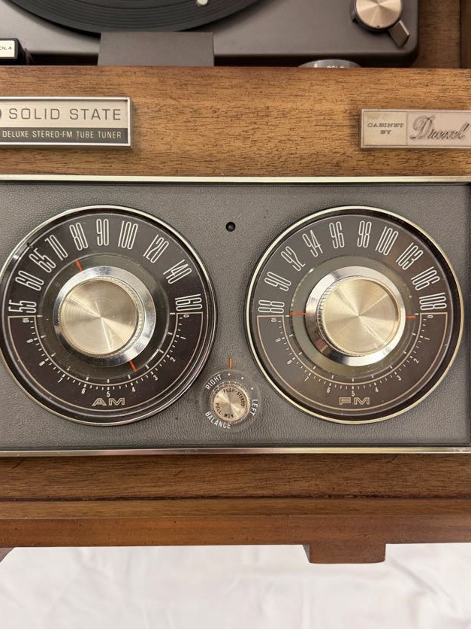 Vintage radio with wooden casing and metallic knobs on a white background