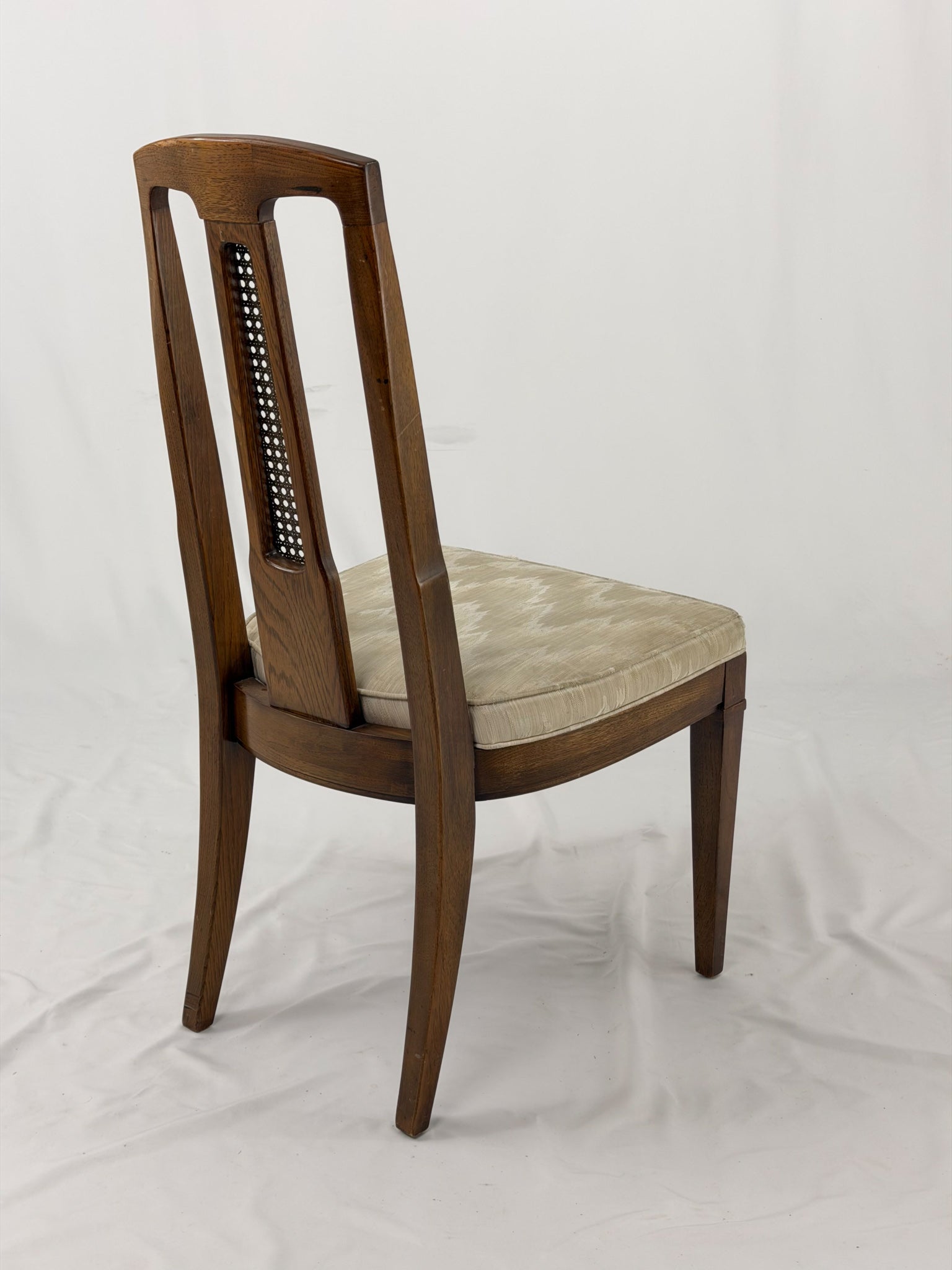 Wooden dining chair with a patterned cushion on a white background