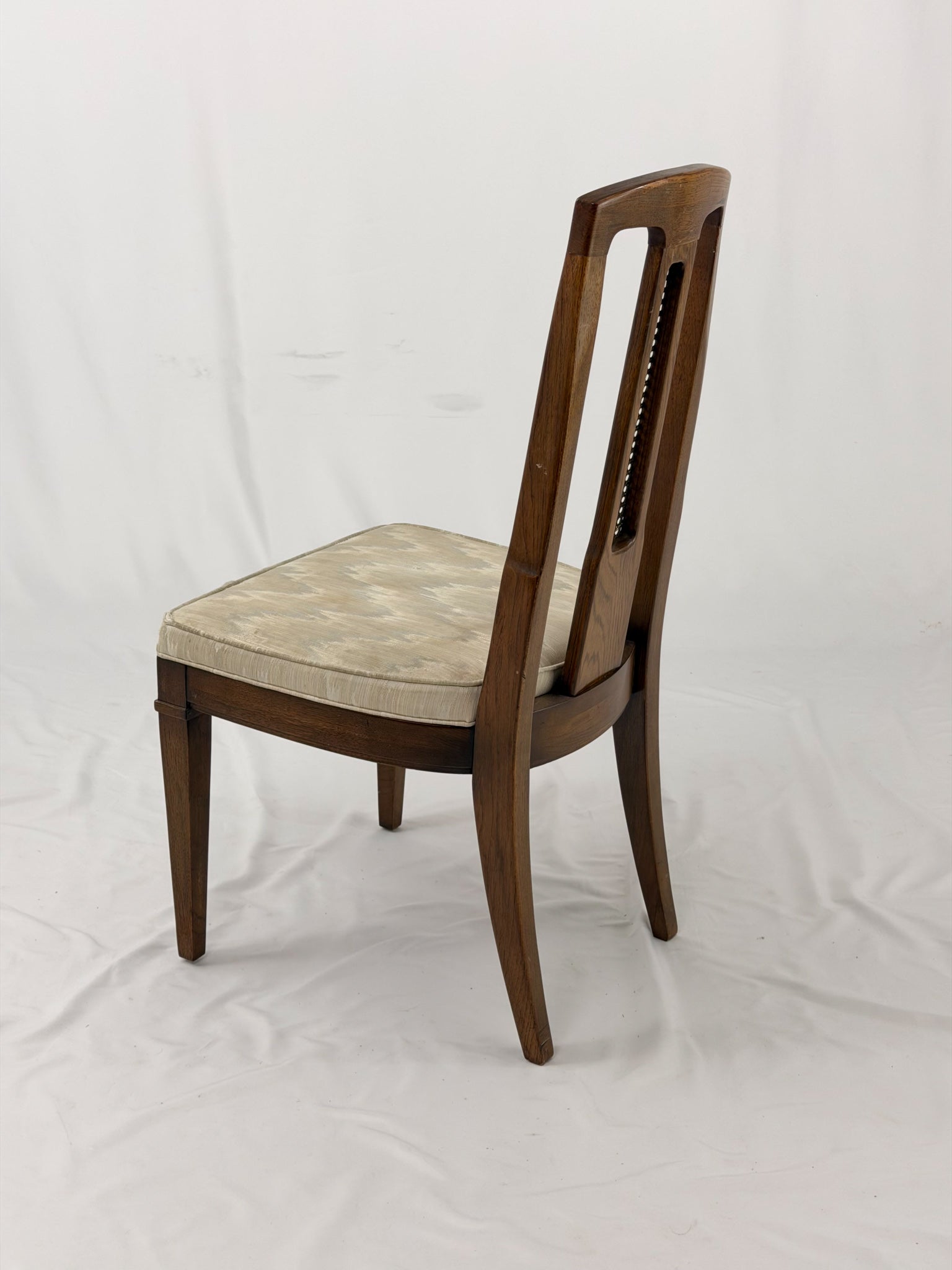 Wooden dining chair with a patterned cushion on a white background