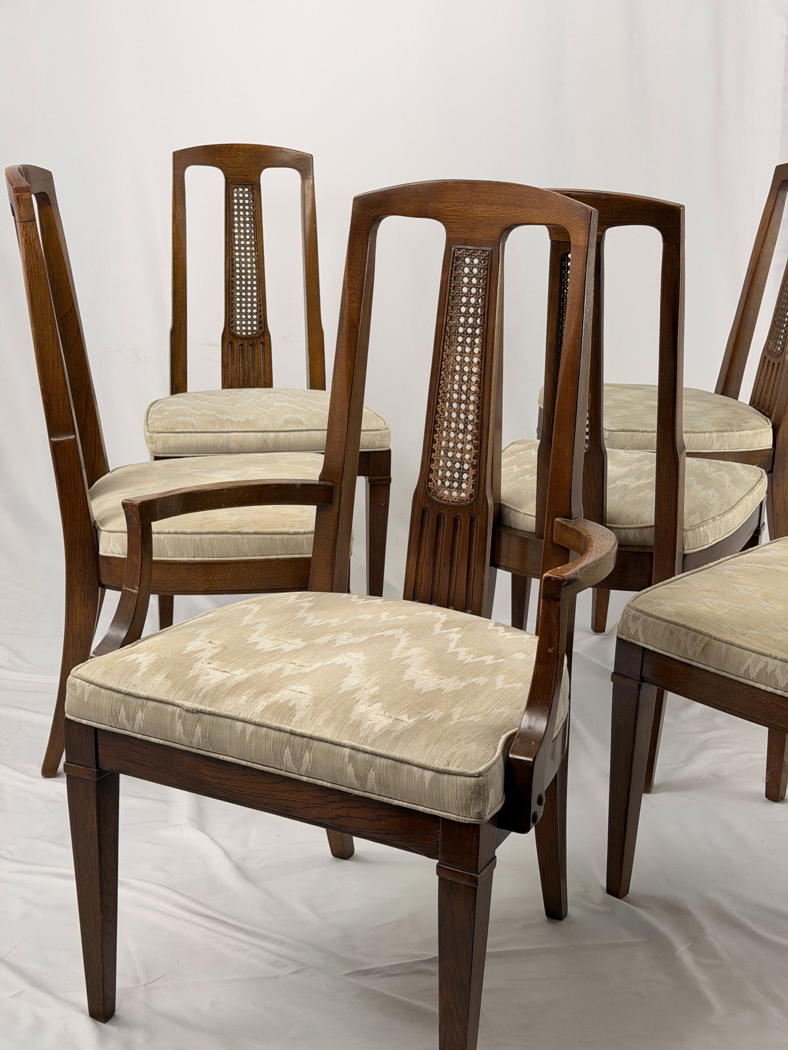 Set of wooden chairs with beige cushioned seats on a white background