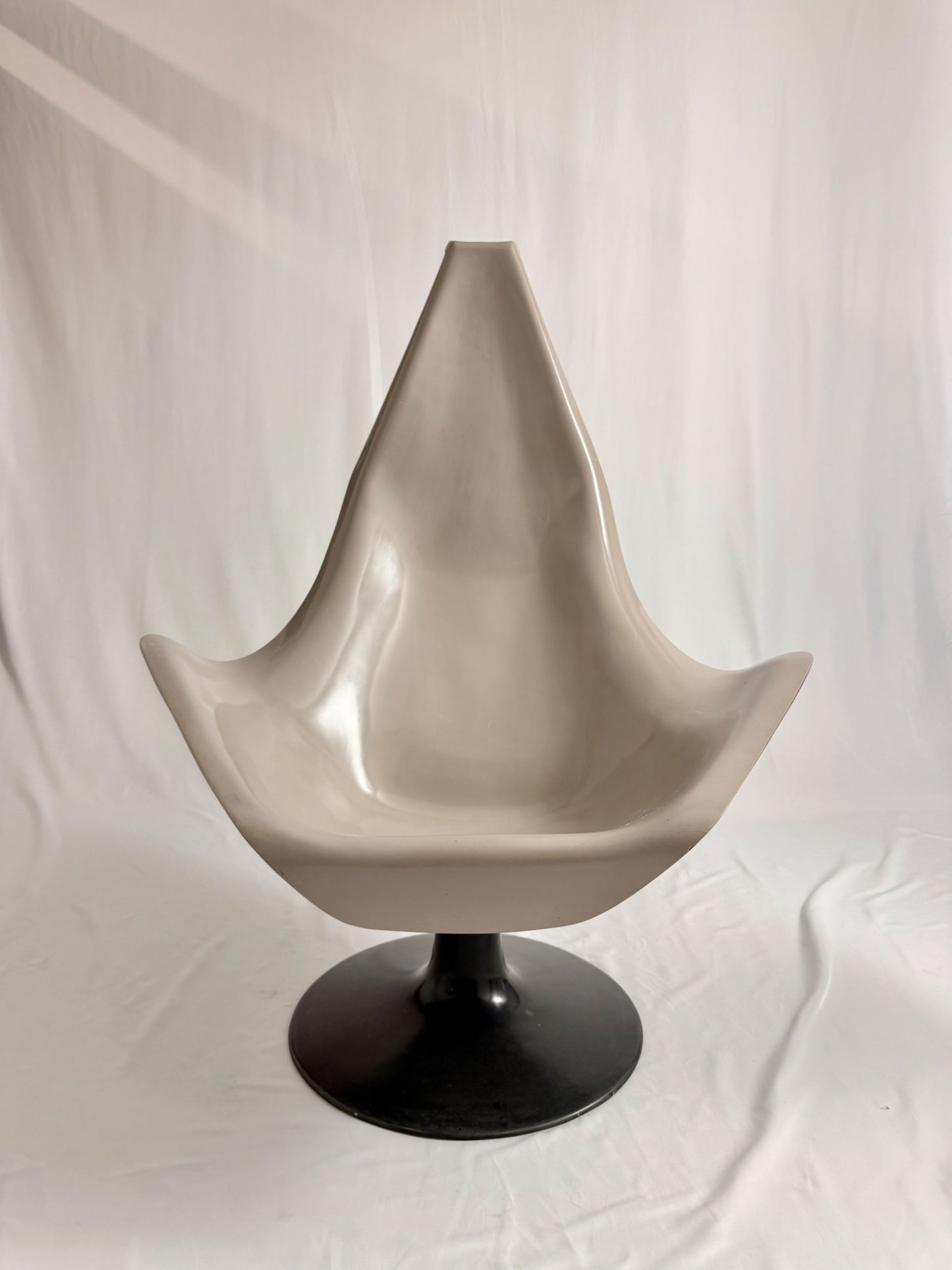 Space Age fiberglass chair with a grey shell and black base on a white background